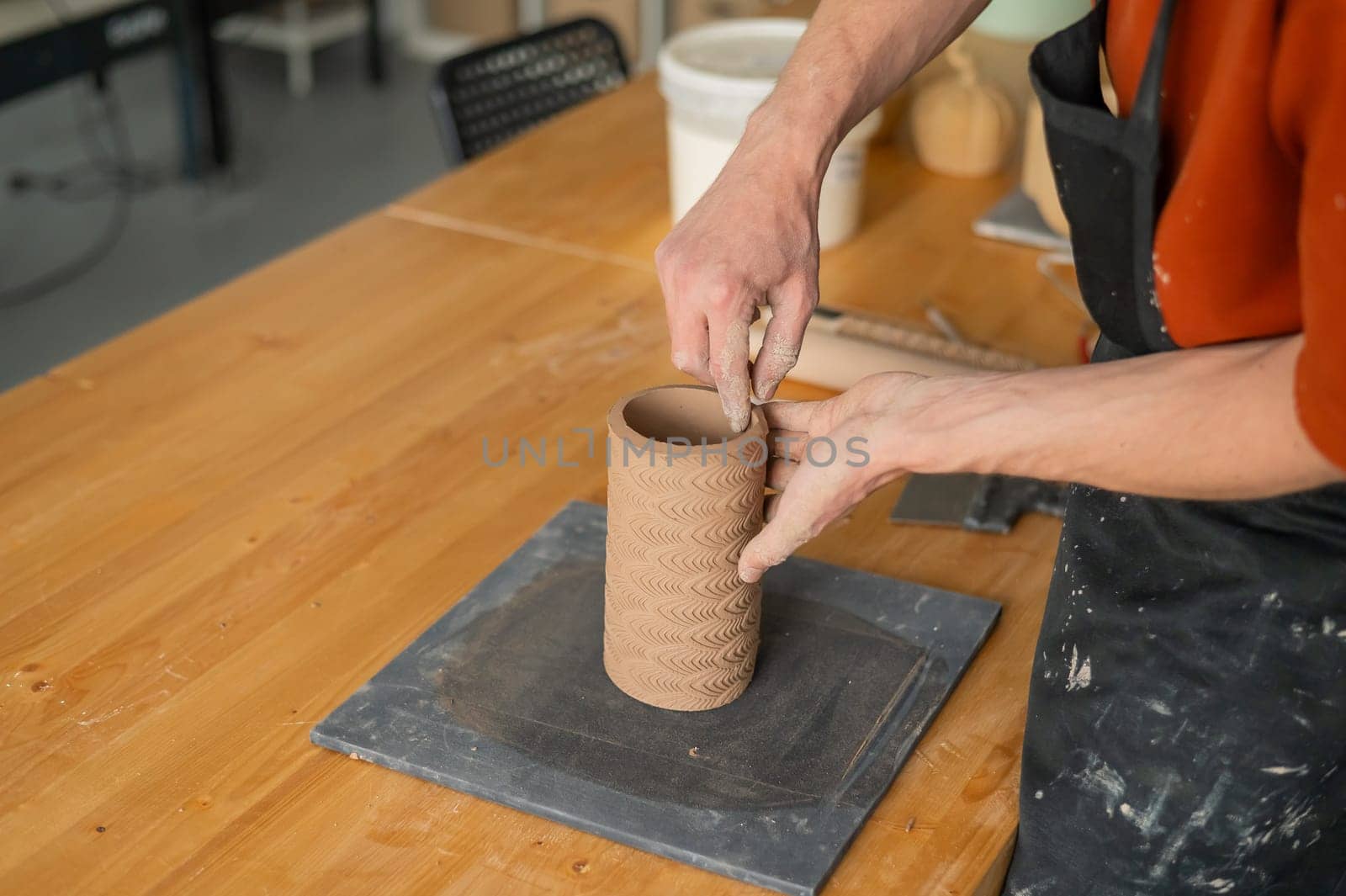Close-up of a man's hands making a patterned cylinder out of clay. by mrwed54