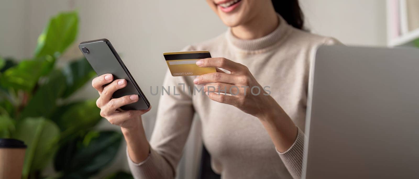Asian female holding smartphone and credit card, using mobile banking app or online shopping app.