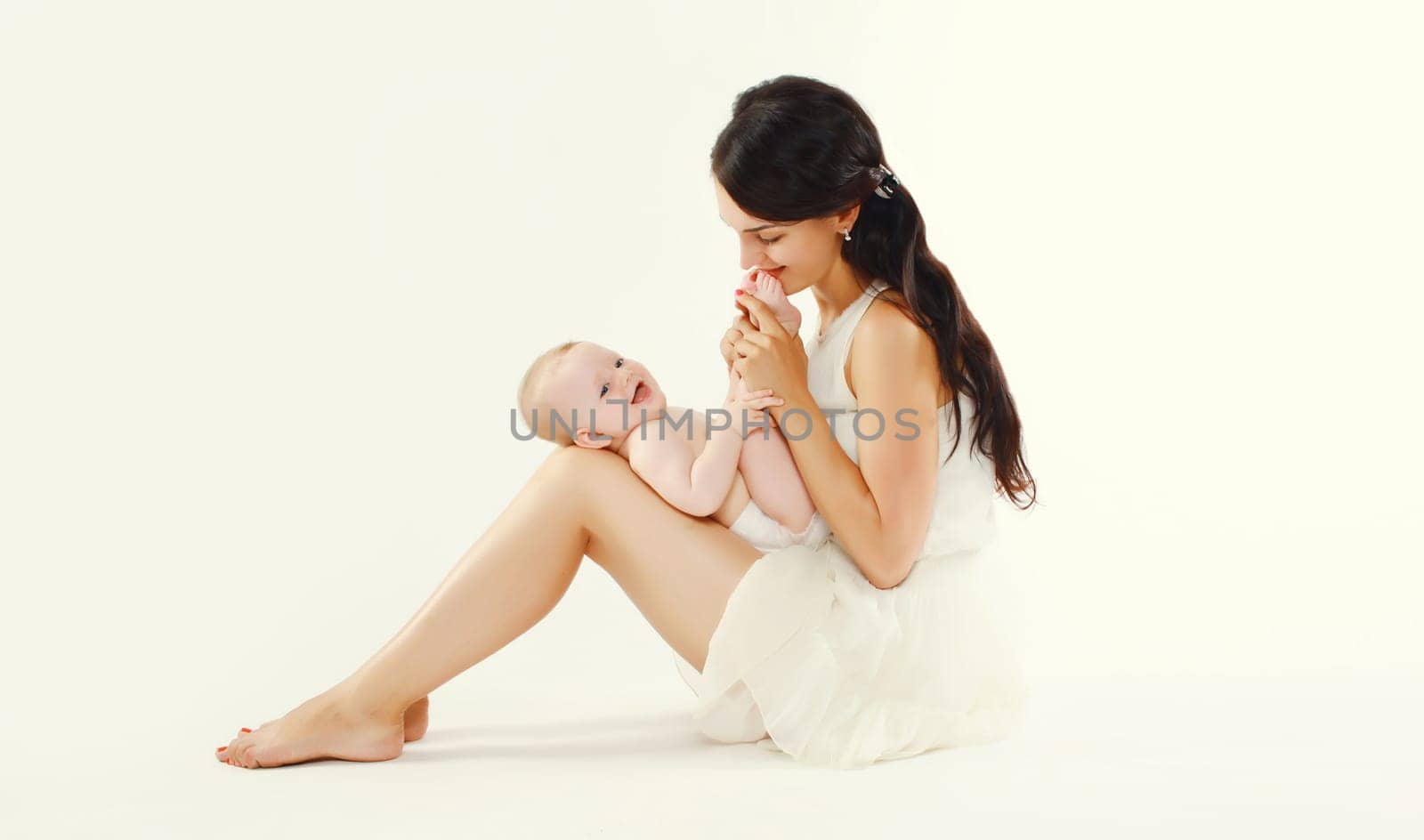 Portrait of happy young mother holding baby on white studio background