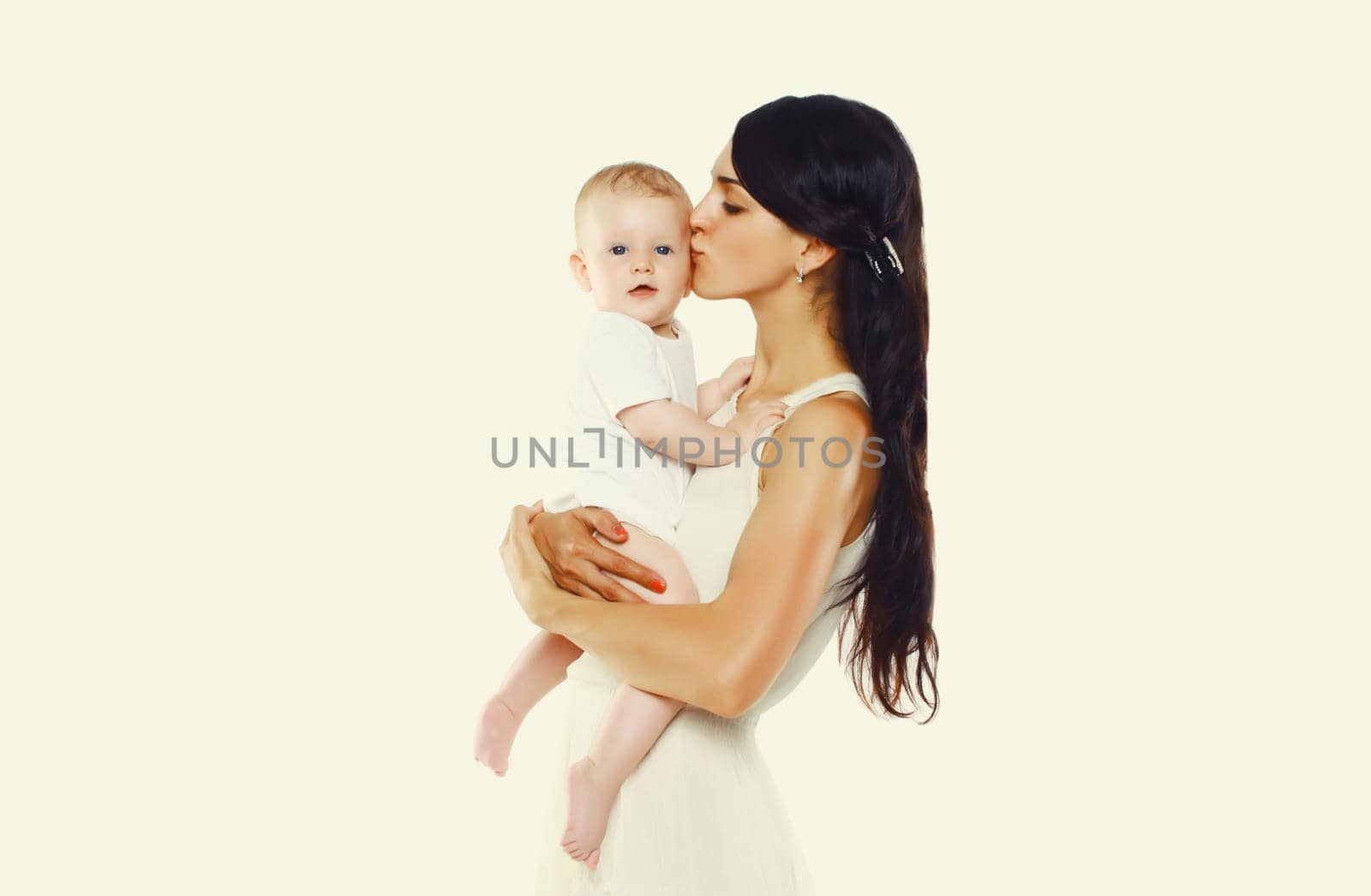 Happy young mother kissing baby on white studio background by Rohappy