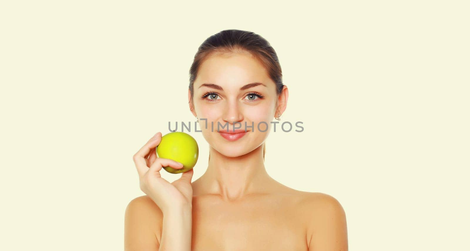 Beauty portrait of brunette young woman holding fresh green apple on white studio background by Rohappy