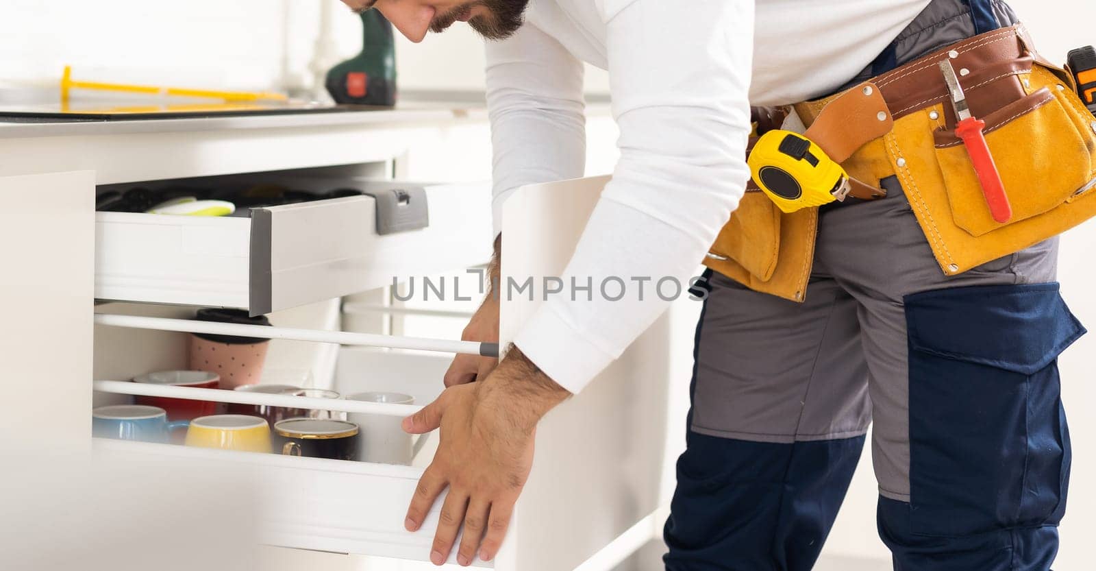 Young man assembling kitchen furniture