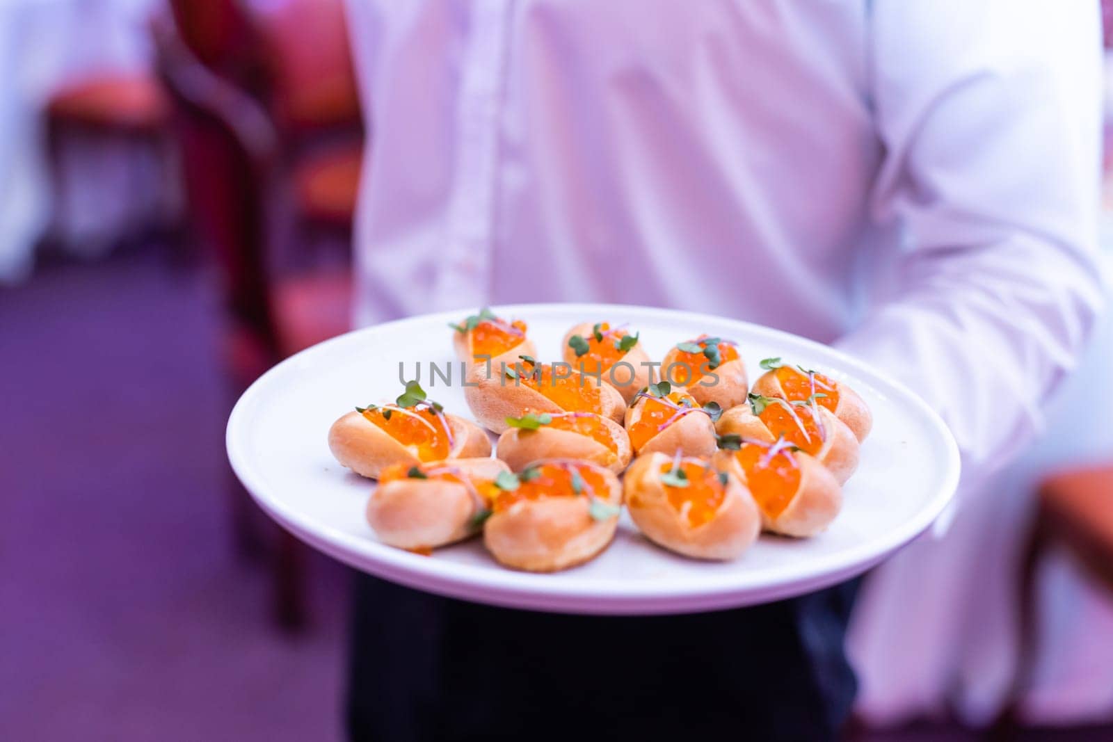 appetizers with caviar on plate at waiter hands inside party event by Andelov13