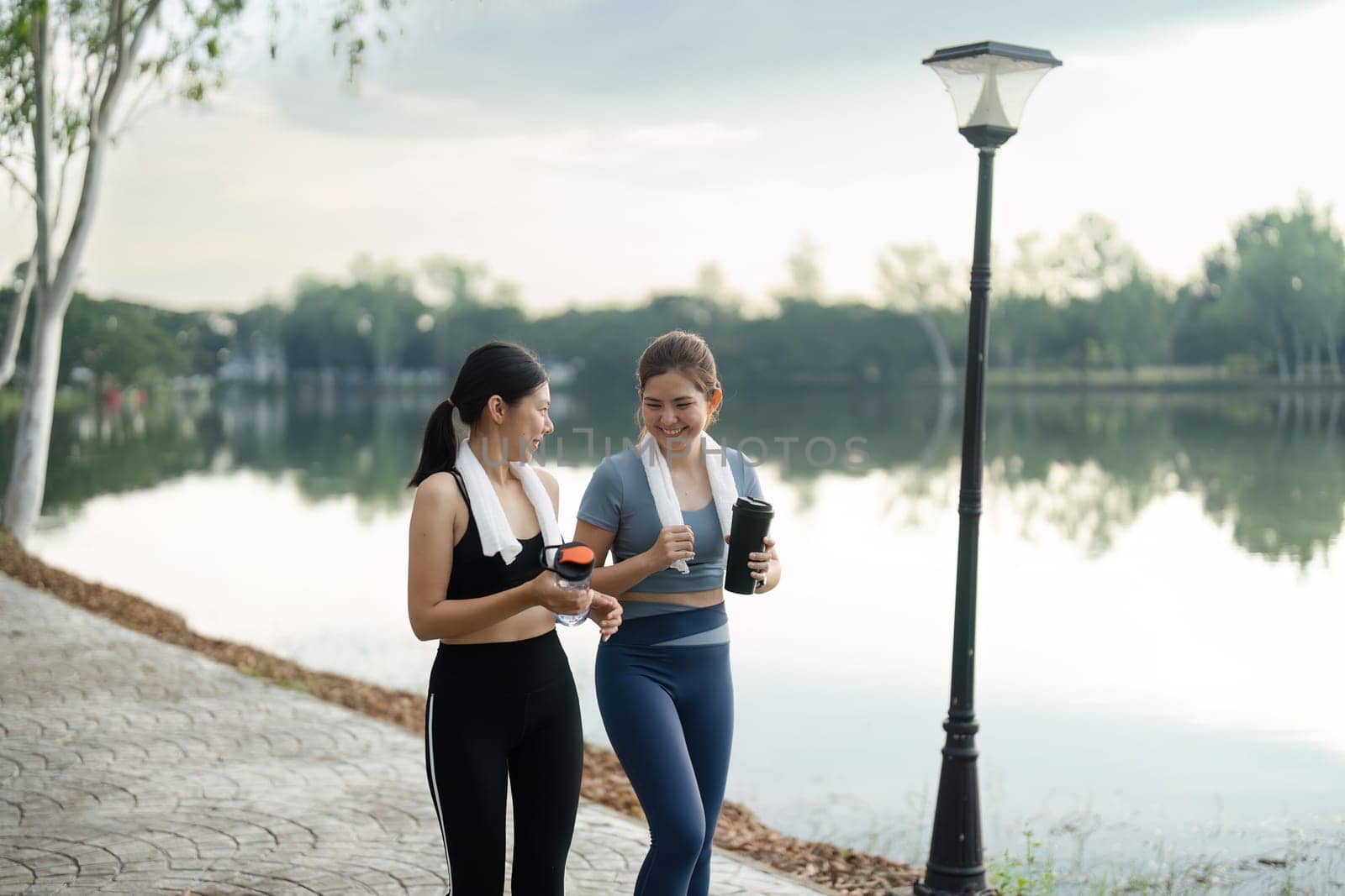 Young women jogger with water bottle in early morning spring sunshine running in town centre. Concept healthy living.