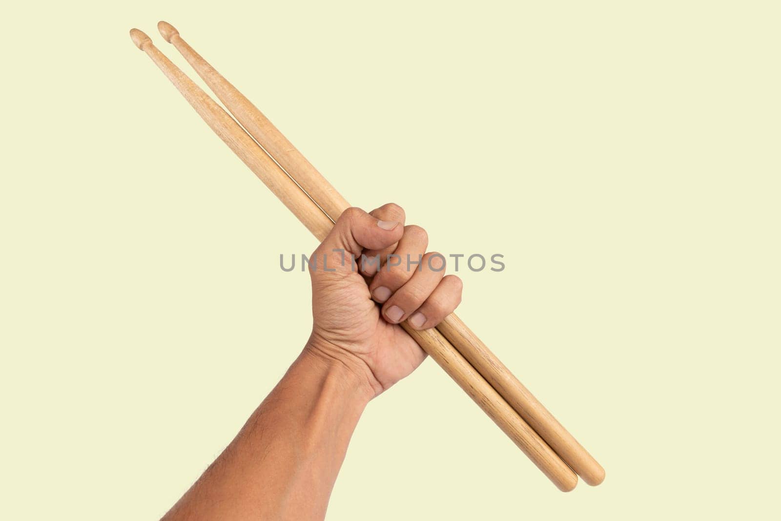 Black male hand holding wooden Drum sticks isolated on green background by TropicalNinjaStudio
