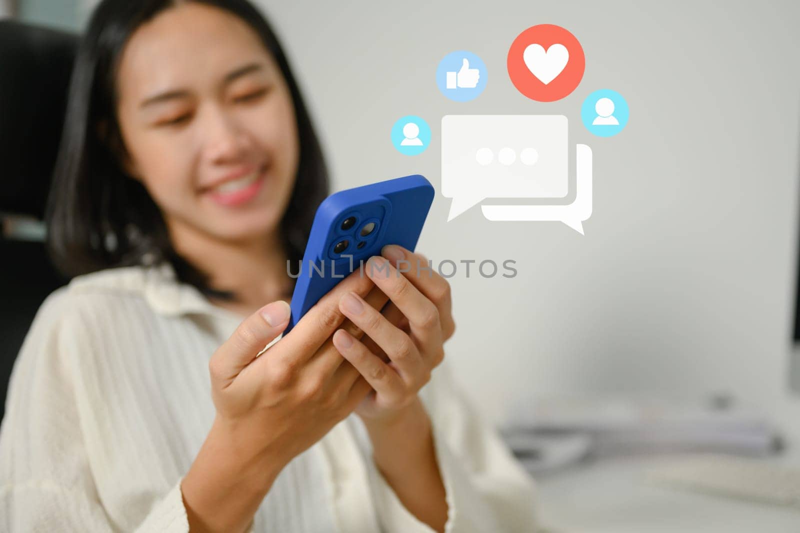 Cheerful young woman checking social media and chatting online on her mobile phone by prathanchorruangsak