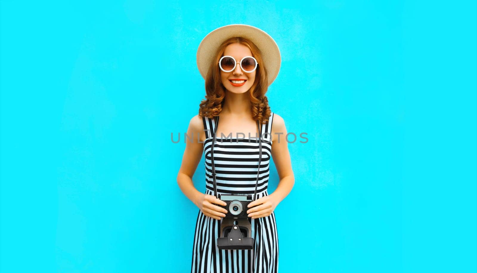 Summer portrait happy smiling young woman photographer with camera in straw hat on blue background by Rohappy