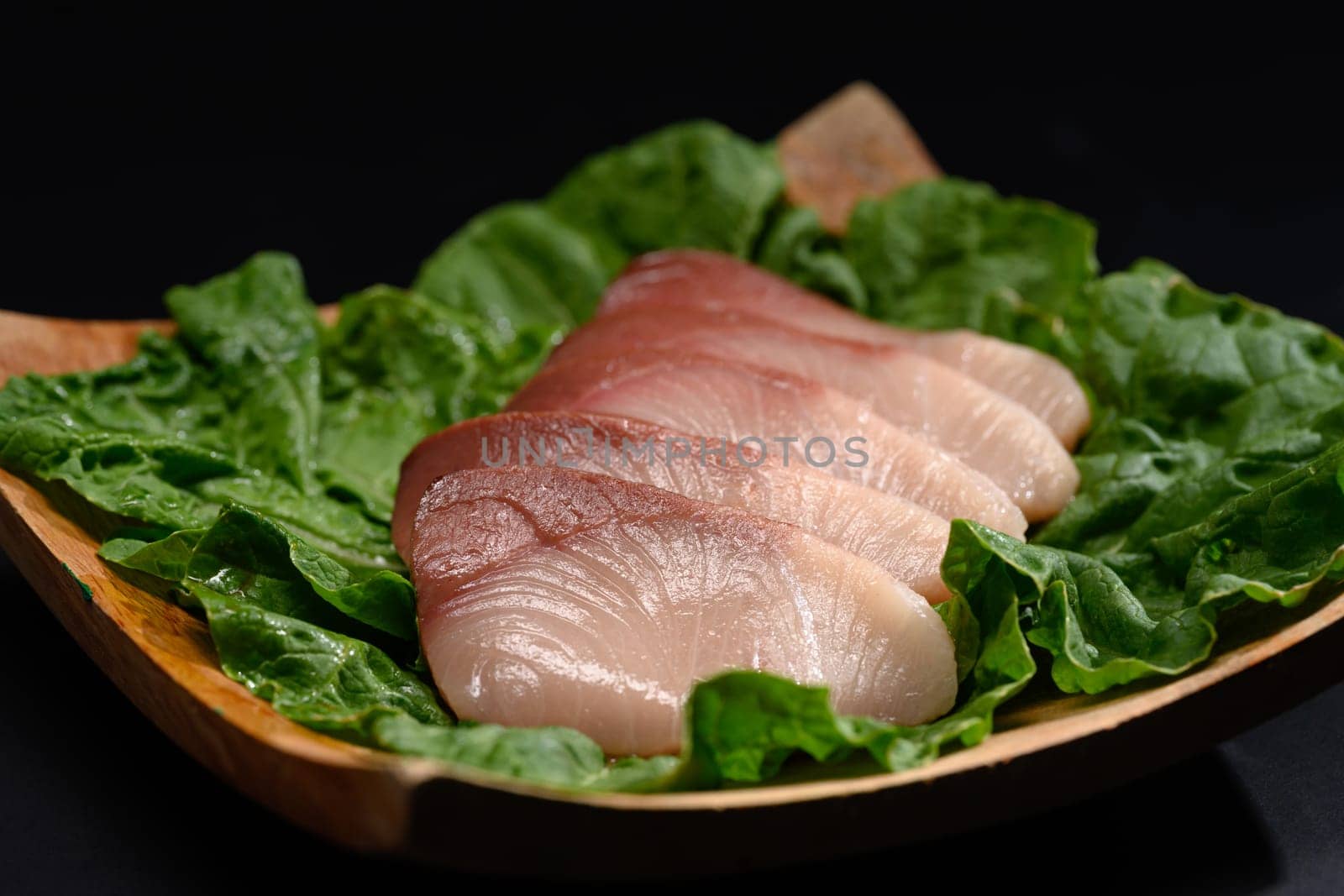 Close up of fresh raw Hamachi sashimi on black plate. Japanese food style.