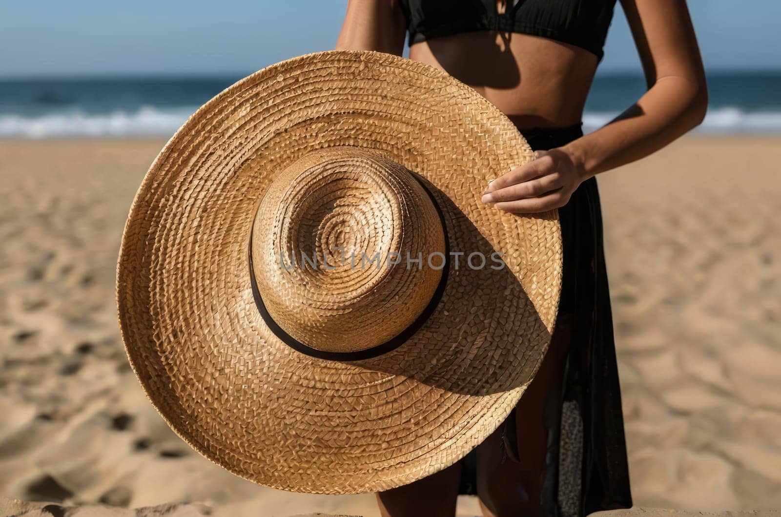 A woman in a spacious straw hat, on a golden beach