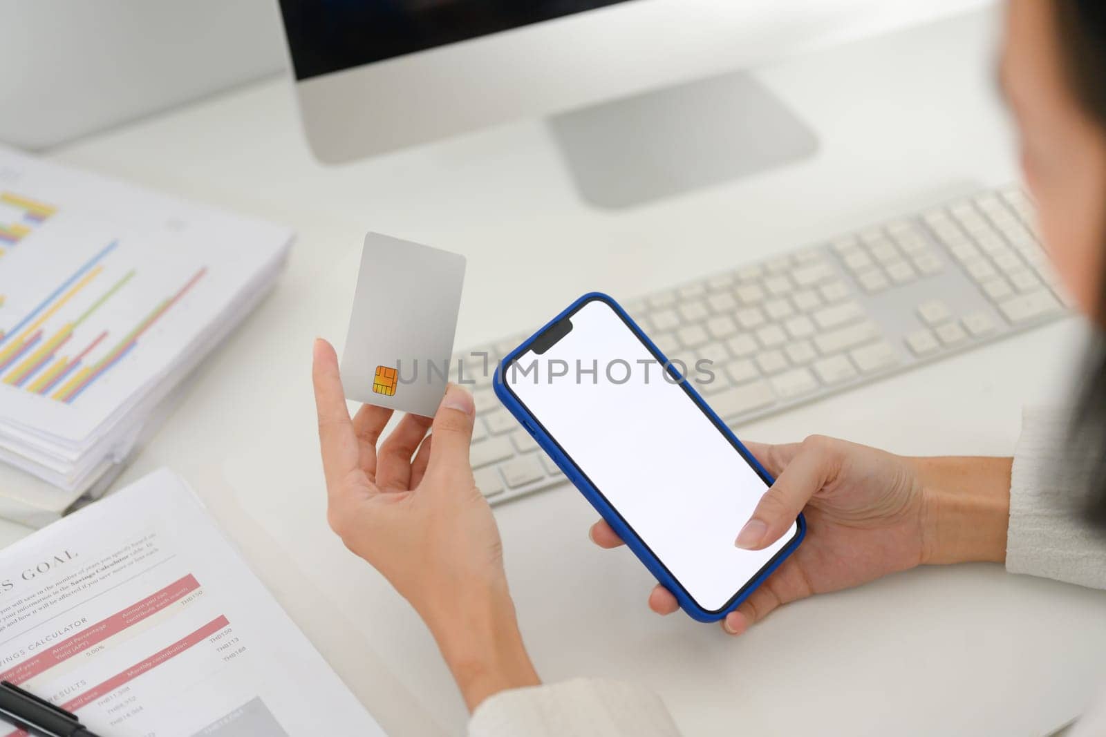 Close up view of businesswoman hand holding credit card and smartphone with blank display.