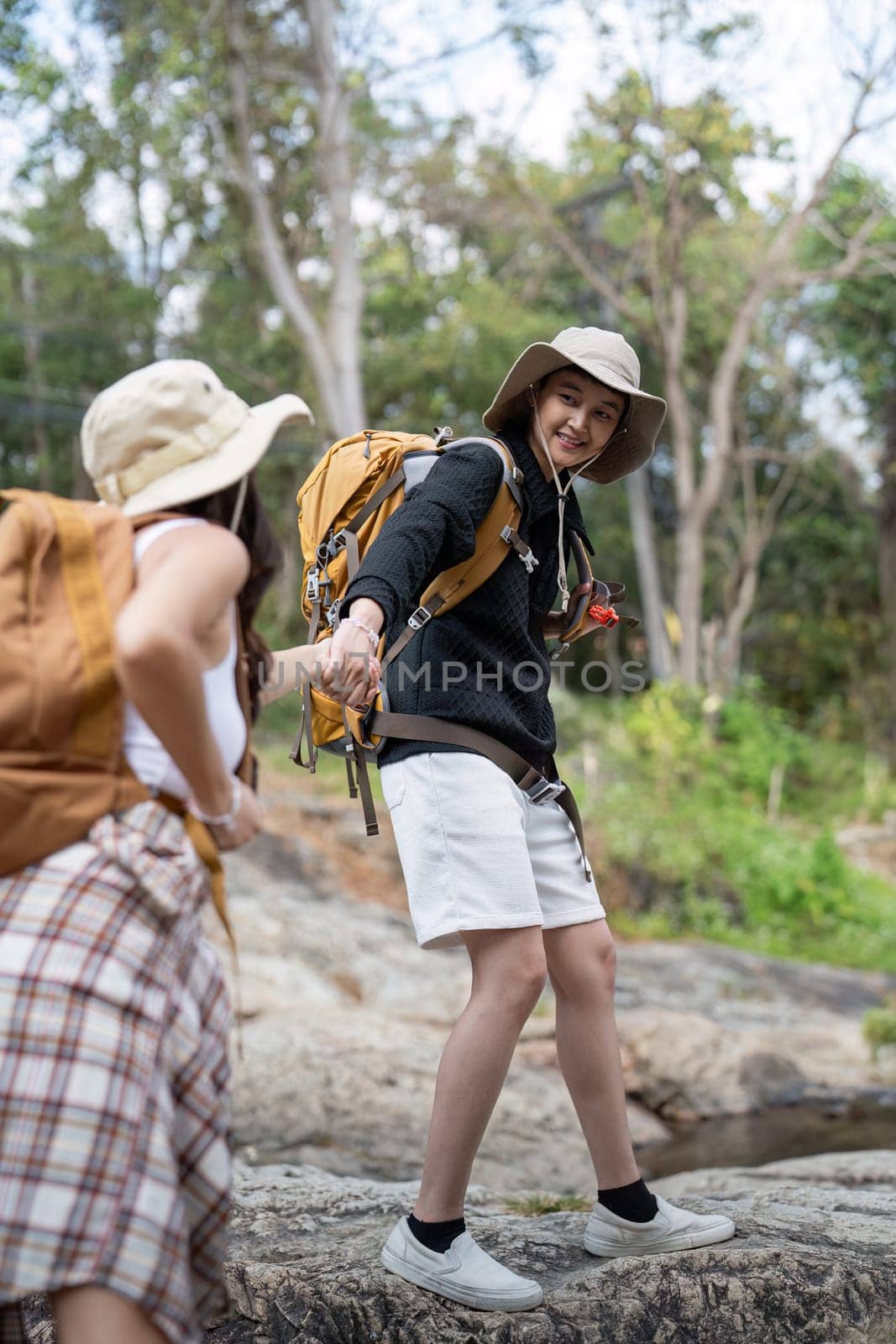 Lovely couple lesbian woman with backpack hiking in nature. Loving LGBT romantic moment in mountains.