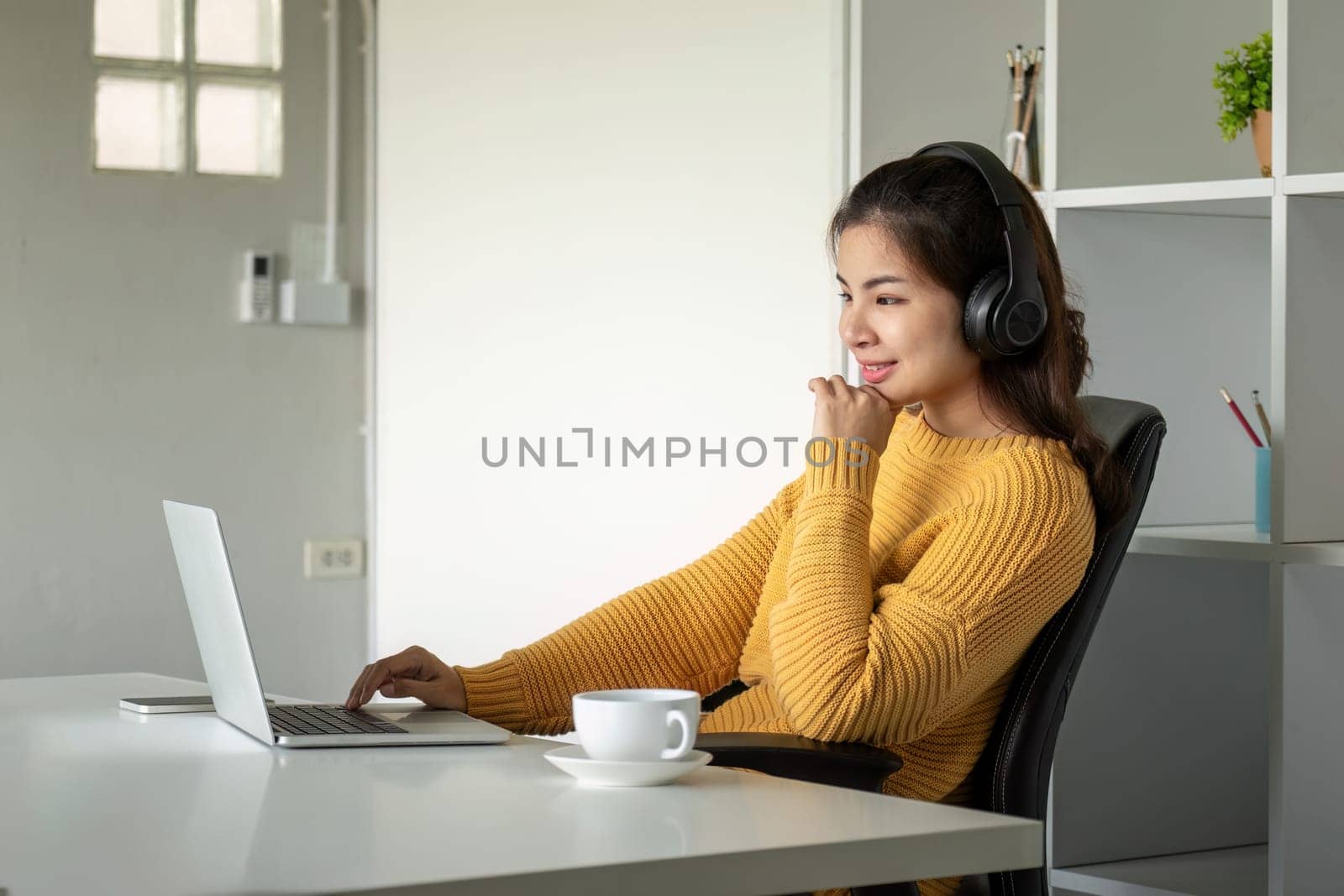 Beautiful young asian woman enjoy listening to music with headphone at desk home, happiness and relaxation concepts.