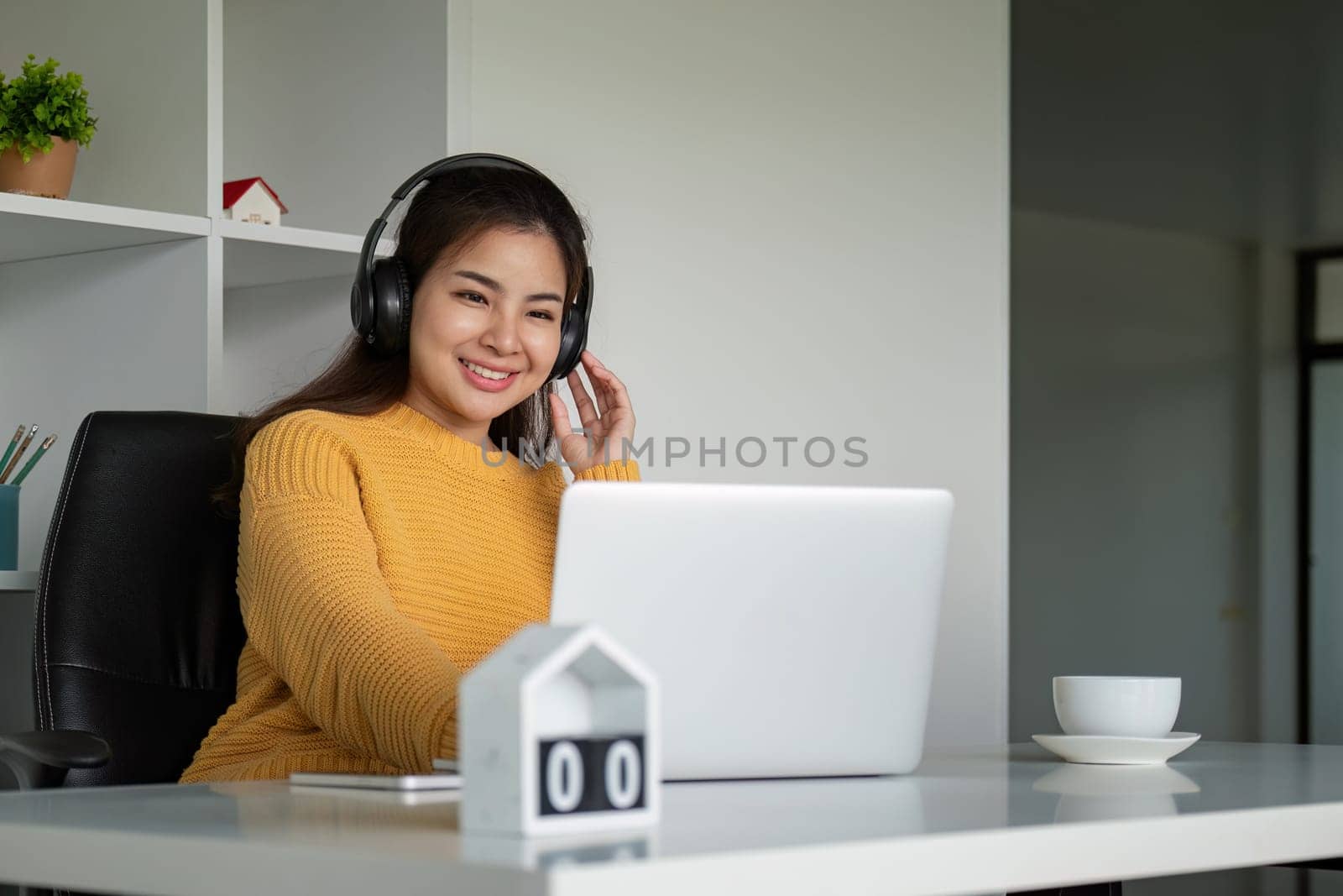 Beautiful young asian woman enjoy listening to music with headphone at desk home, happiness and relaxation concepts by nateemee