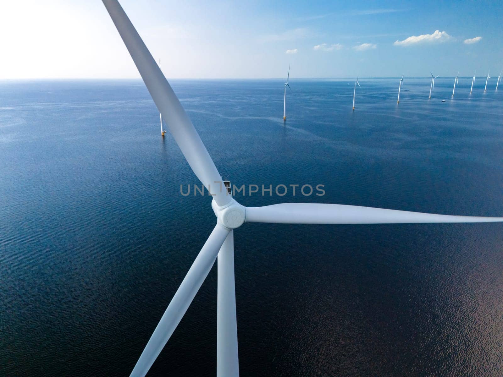 A mesmerizing display of wind farm turbines gracefully spinning amidst the vast expanse of the ocean, harnessing the power of the wind to generate renewable energy.