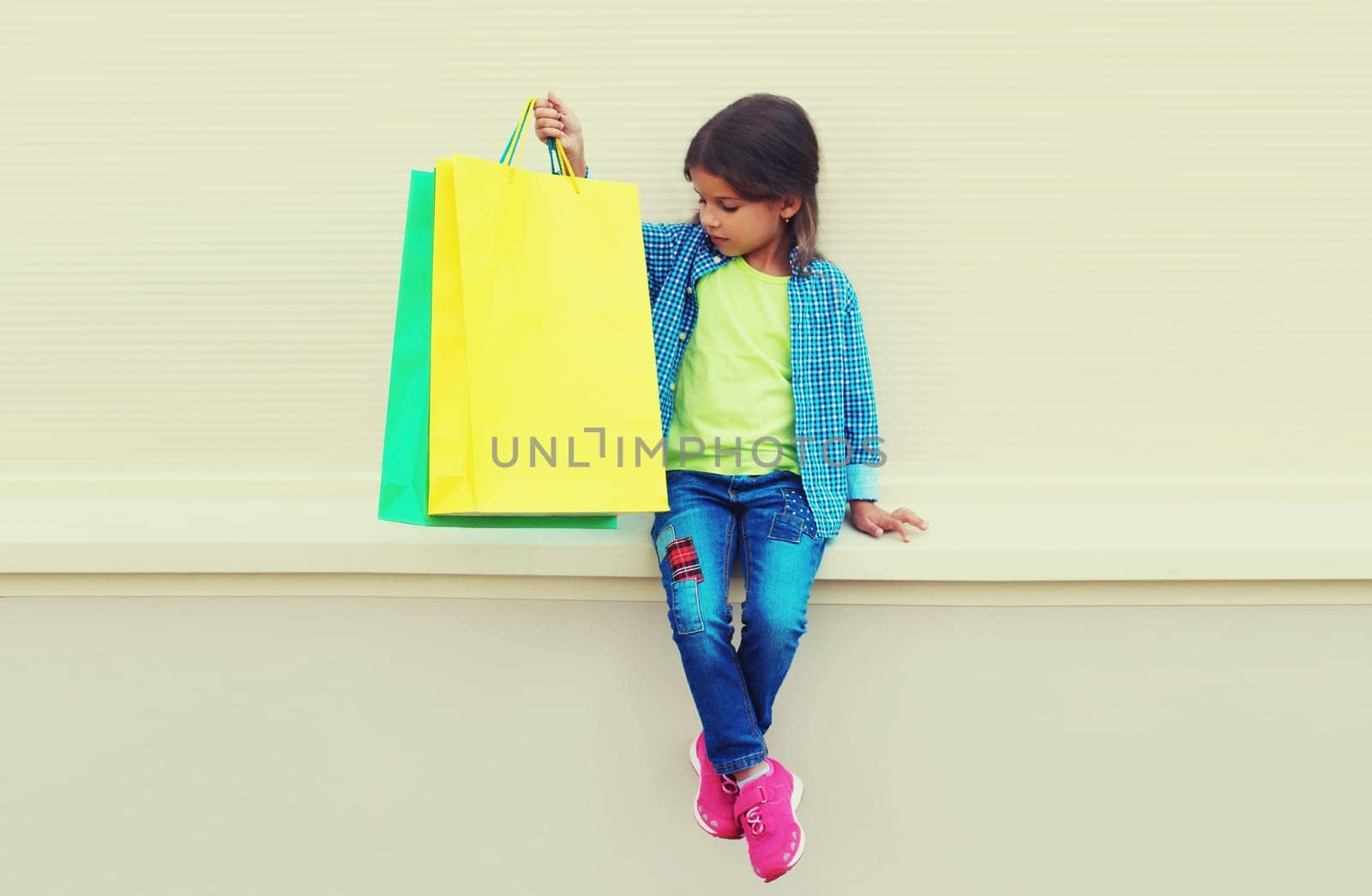 Little girl child with colorful shopping bags posing on city street
