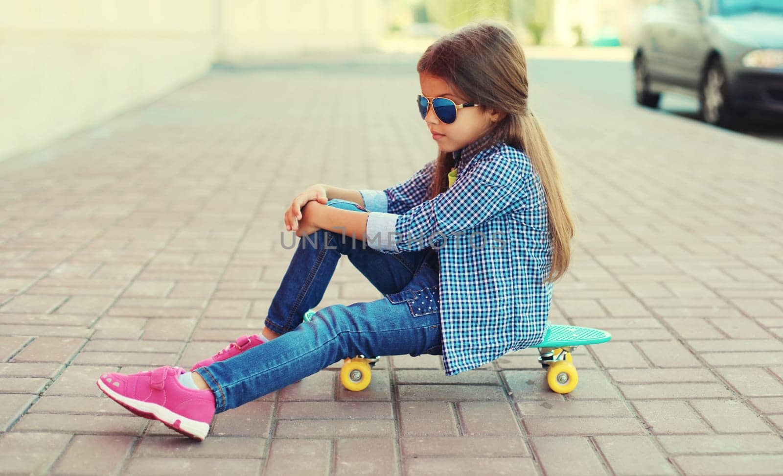 Stylish little girl child posing with skateboard on city street by Rohappy