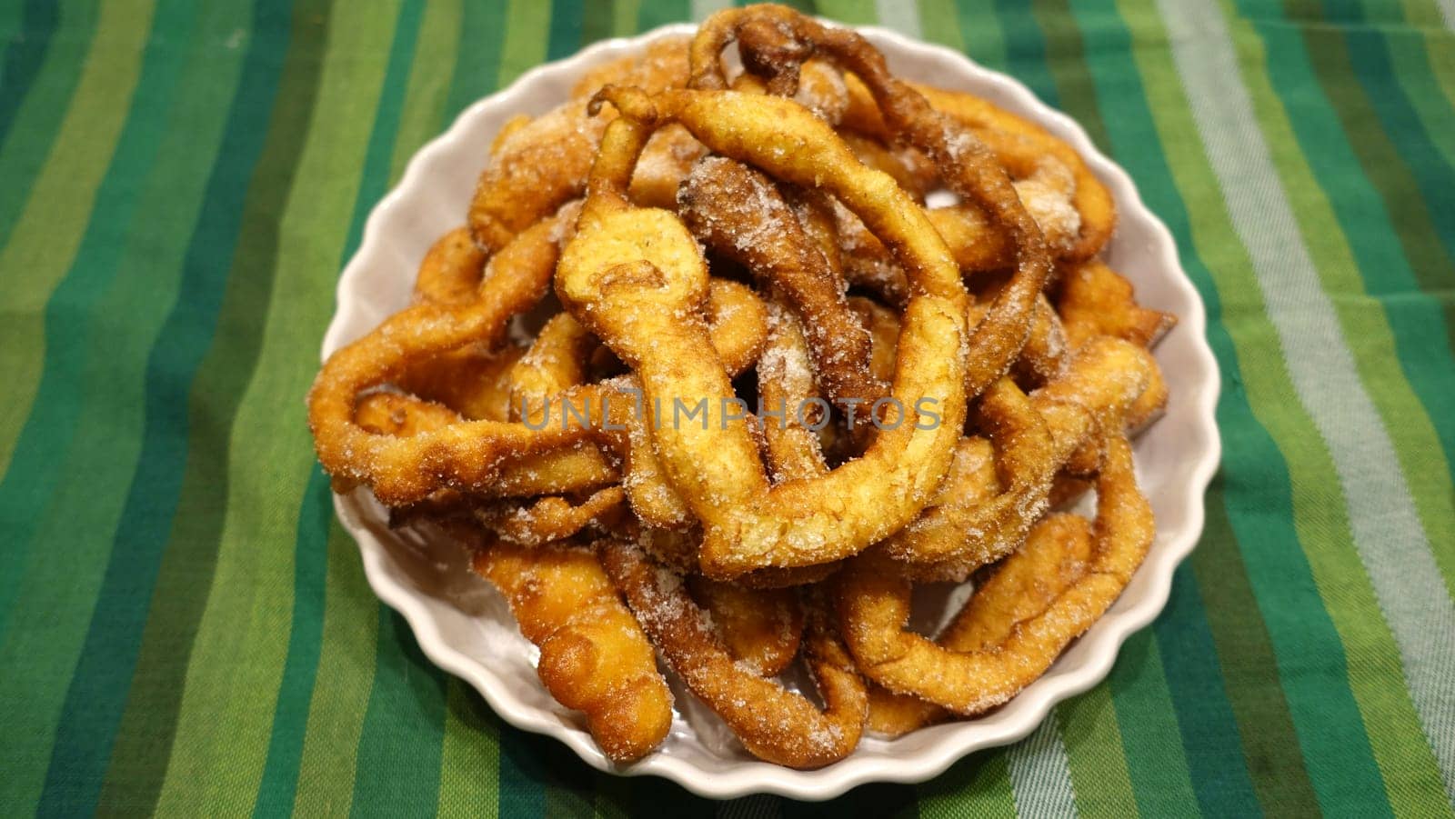 A tray of fried dough snakes with sugar ready to eat. Traditional Italian Frittelle.