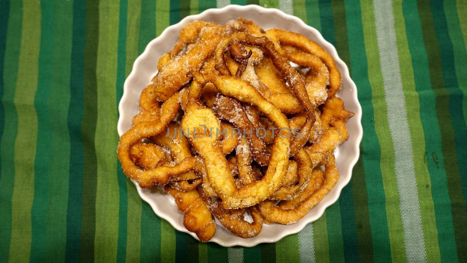 A tray of fried dough snakes with sugar ready to eat. Traditional Italian Frittelle.