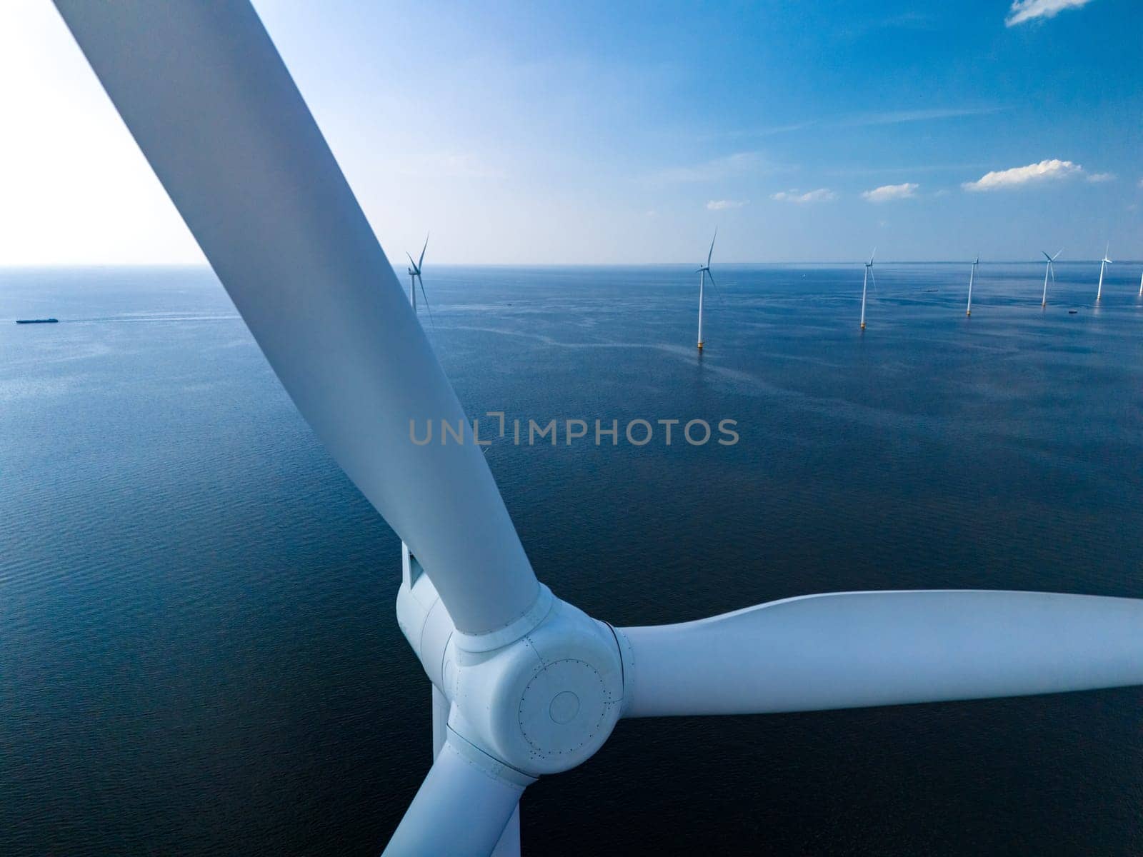 A breathtaking aerial view of a wind farm in the ocean, showcasing rows of towering windmill turbines generating renewable energy in the Netherlands Flevoland.