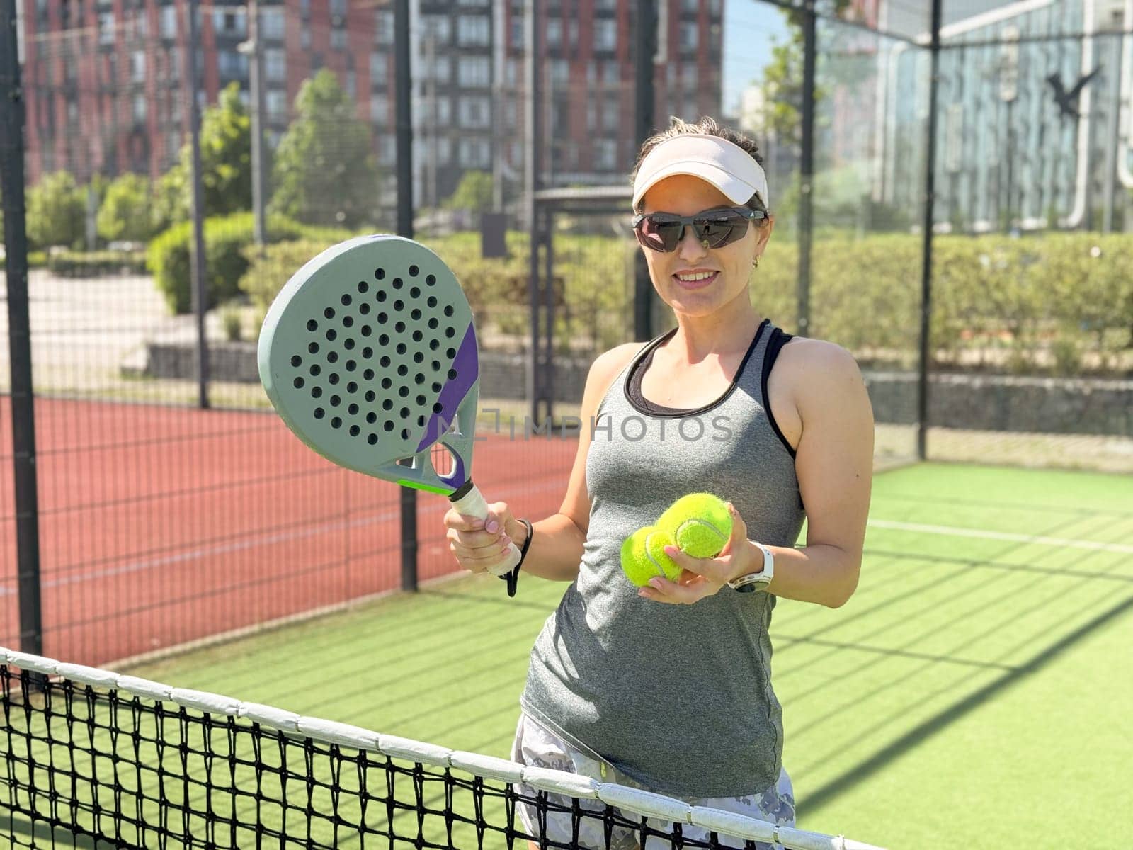 Portrait of active emotional woman playing padel tennis on open court in summer, swinging racket to return ball over net .. High quality photo