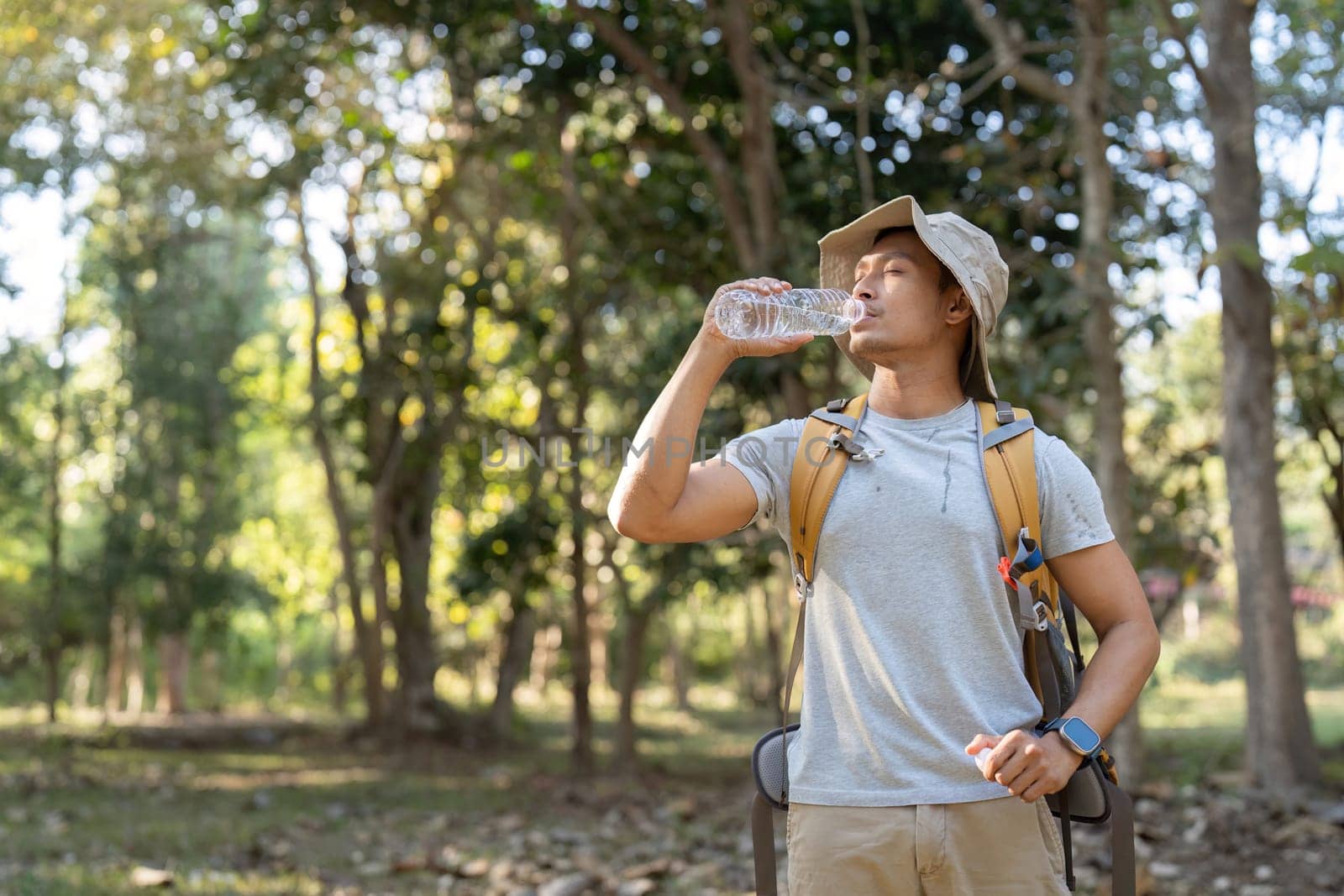 Traveler hiking man carrying a backpack on the back and walking in national park. man asian is rest by drink water by nateemee