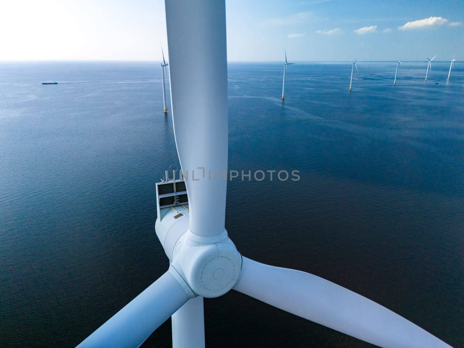 A majestic wind turbine stands tall in the middle of the ocean, harnessing the power of the wind to generate clean, sustainable energy for the surrounding area by fokkebok