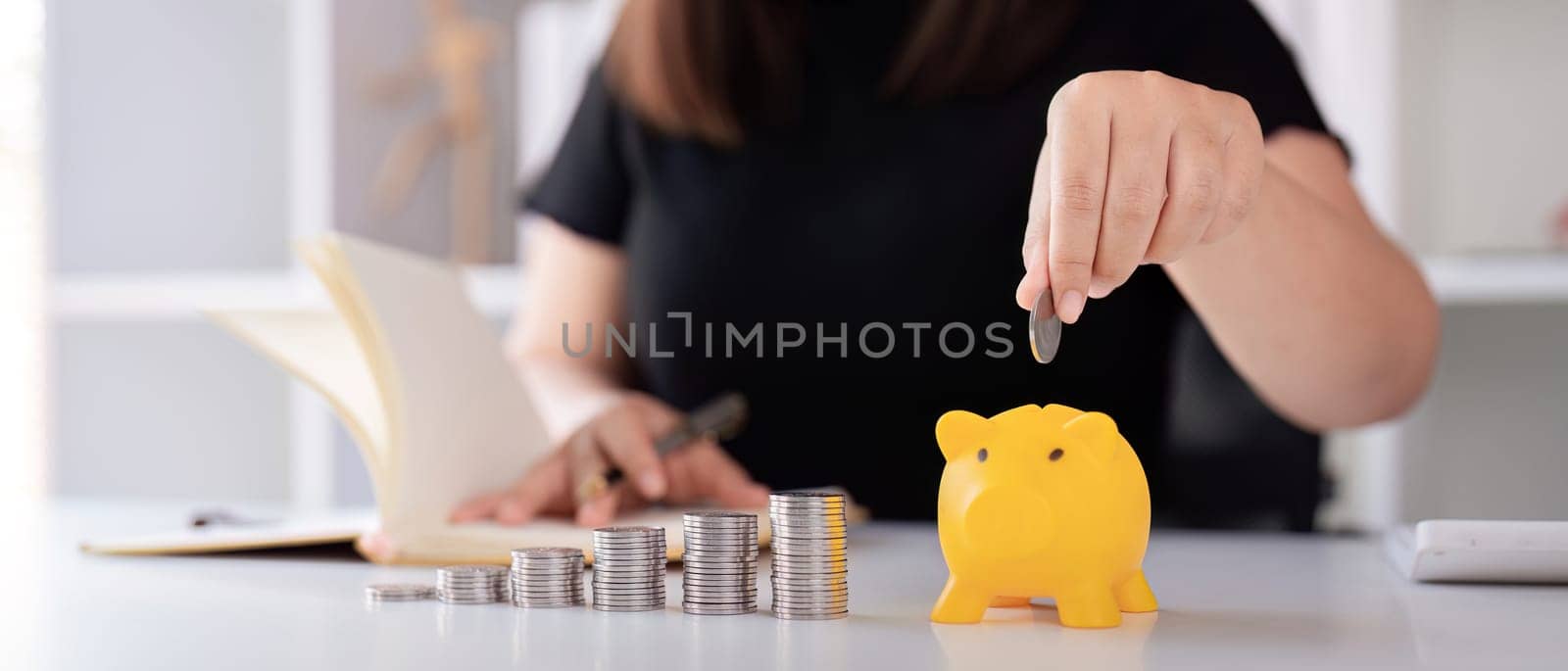 Woman hand putting coins in a piggy bank for save money and saving money concept by nateemee