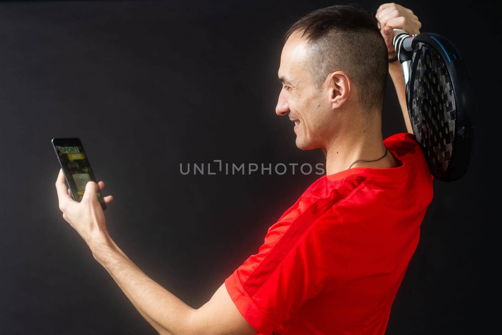 man holding paddel racket and smartphone with bet black background by Andelov13