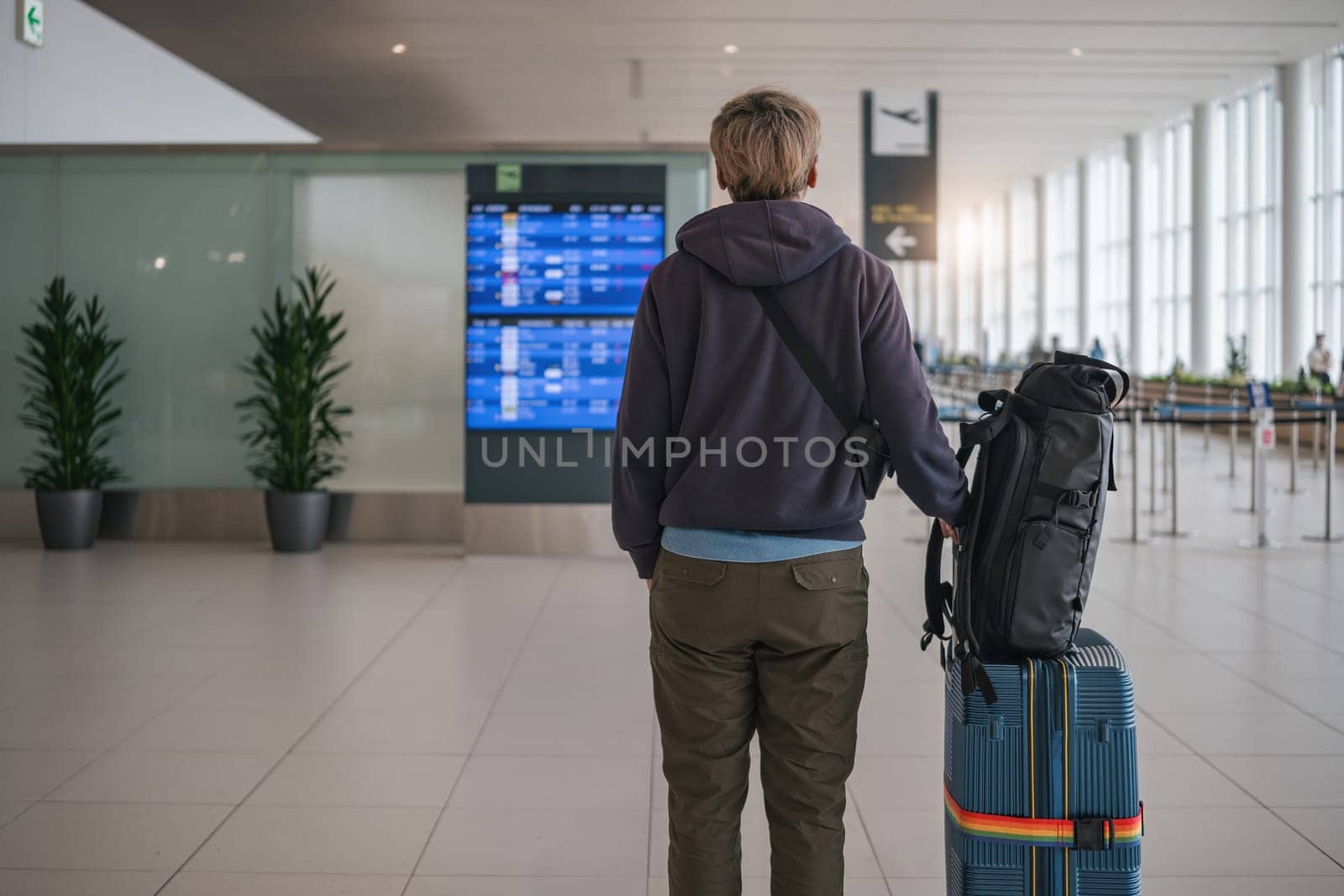 Young Asian man in international airport looking at flight information board, checking her flight by wichayada