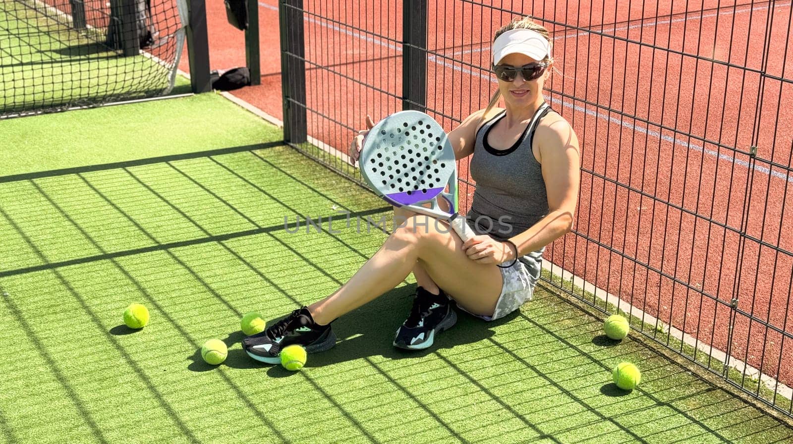 Portrait of active emotional woman playing padel tennis on open court in summer, swinging racket to return ball over net .. High quality photo