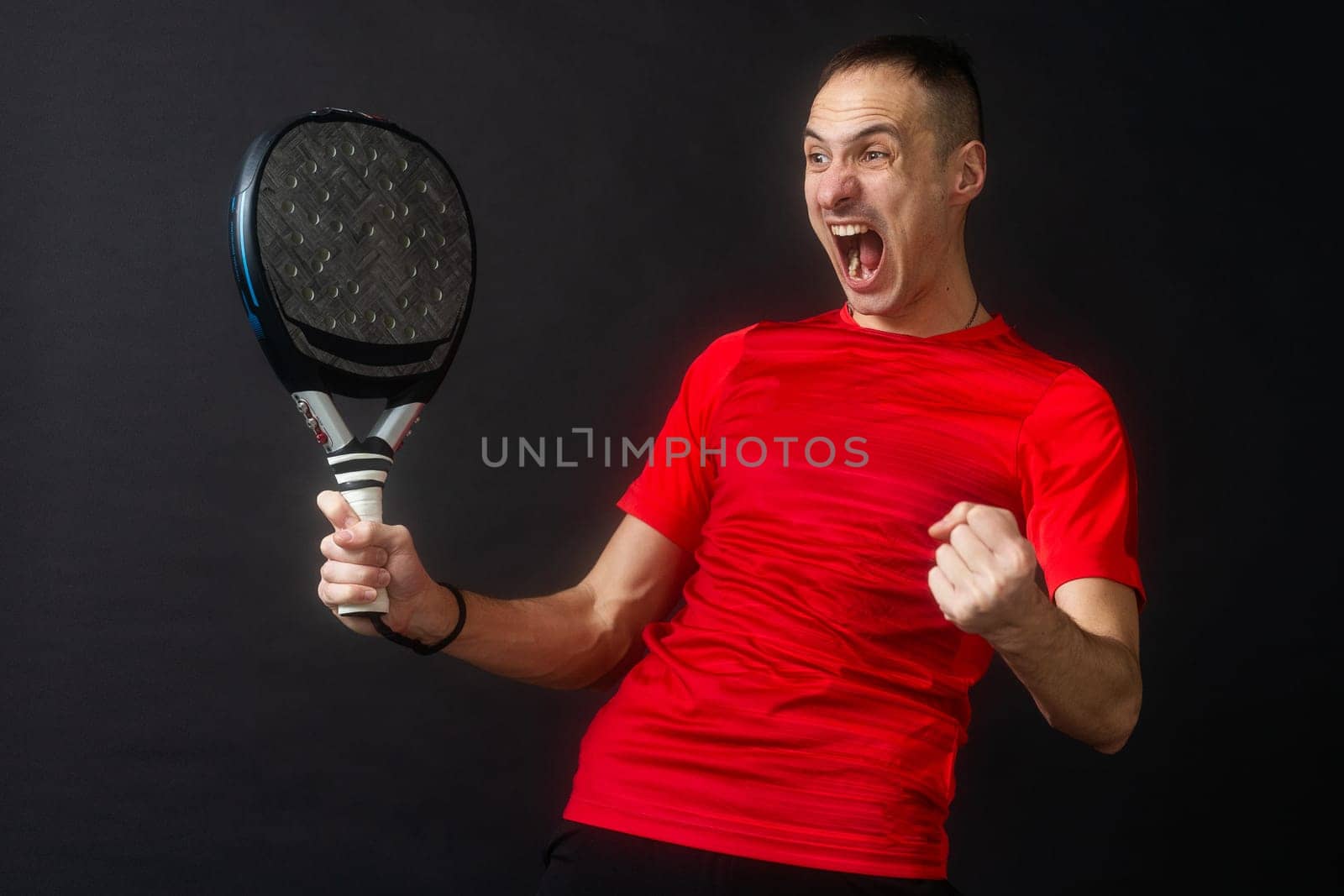 Smiling man with racket and paddle ball dressed in sport clothes isolated background. Front view. High quality photo