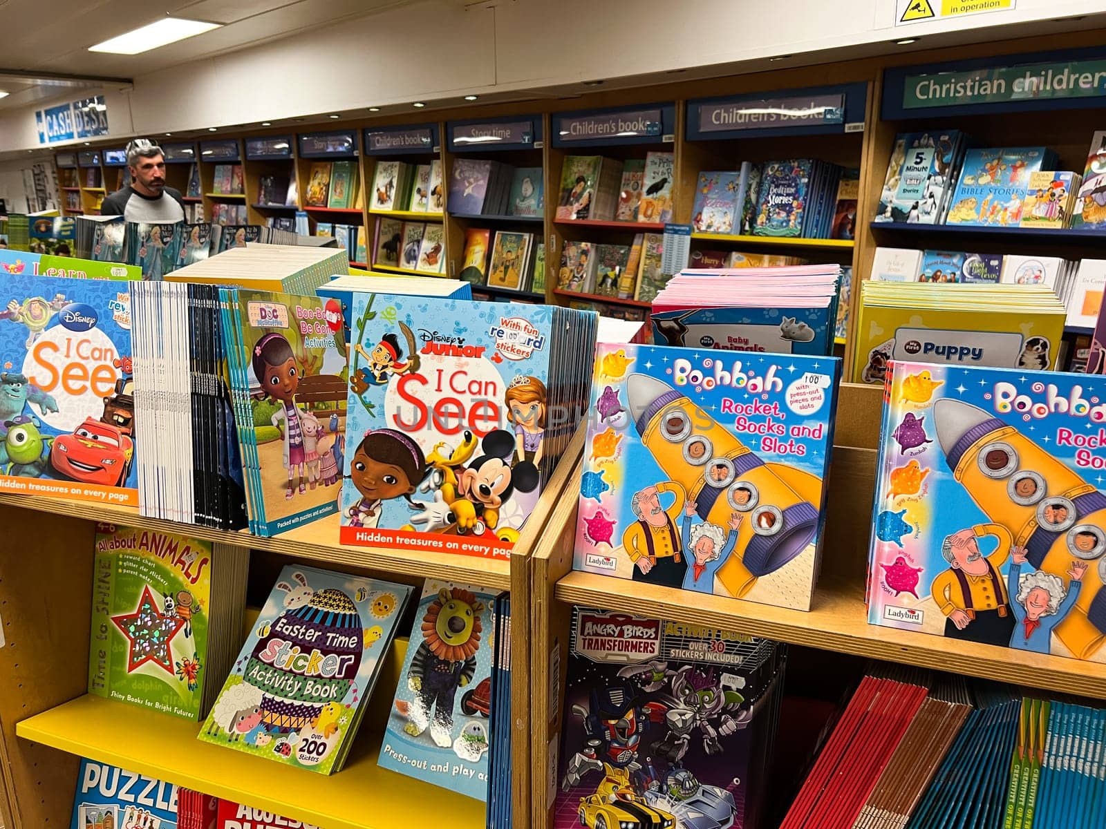 Colorful educational picture books and comics stand on the shelves in a bookstore. High quality photo