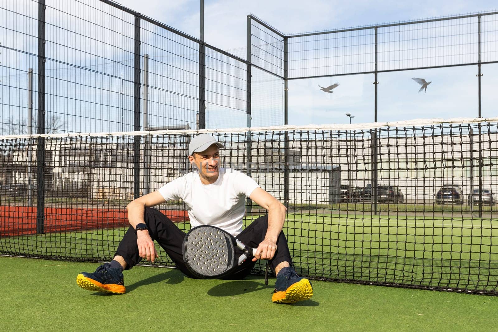 European man holding padel racquet in hand and ready to return ball while playing in court. High quality photo