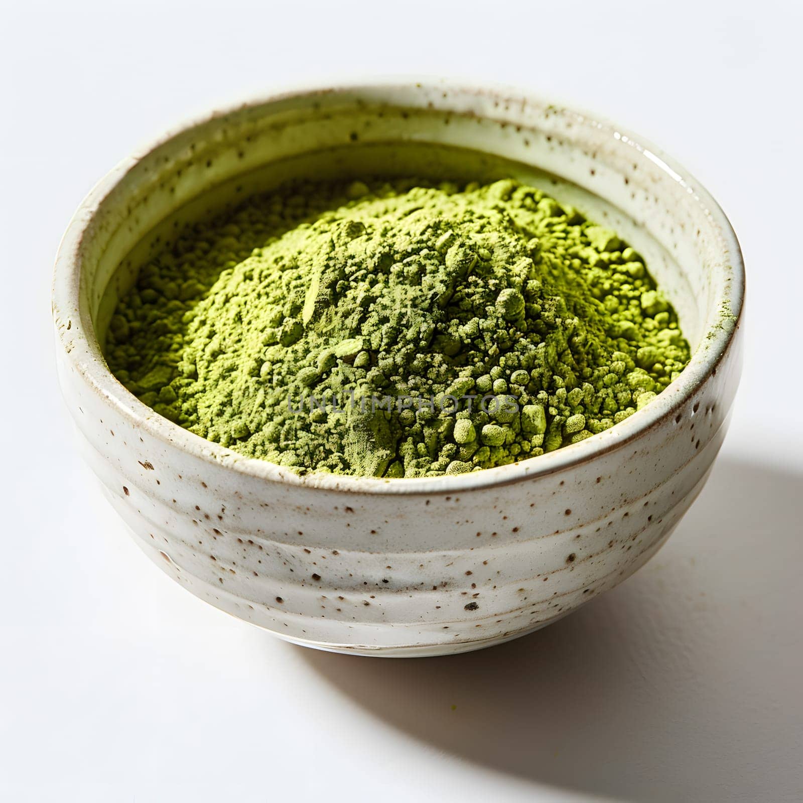 A white dishware filled with vibrant green plantbased powder, ready to be used as an ingredient in a delicious recipe. Perfect condiment for a flavorful cuisine dish