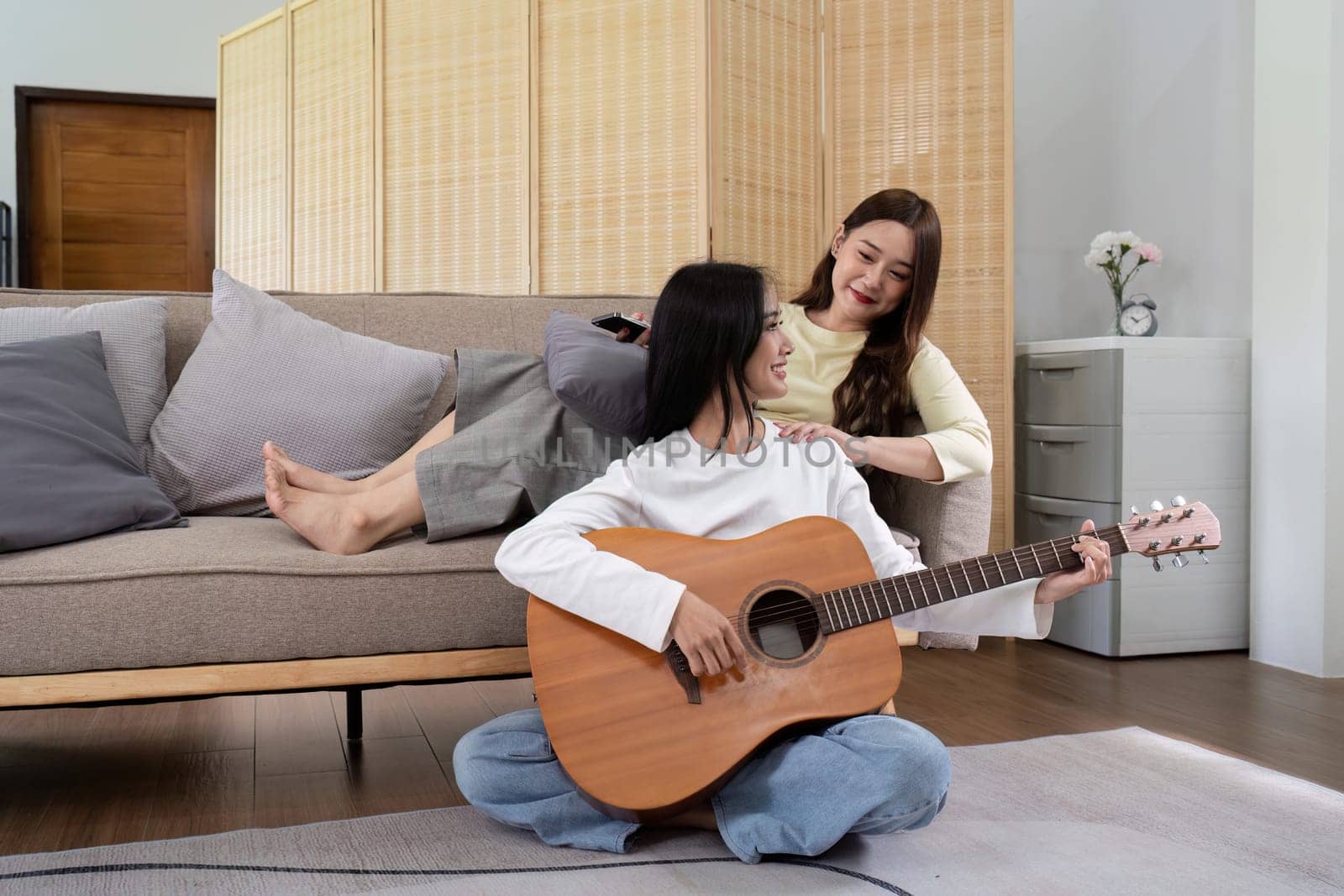 Asian young lover lesbian couple playing guitar with relax and happy moment in living room LGBT relationship in lifestyle concept by nateemee