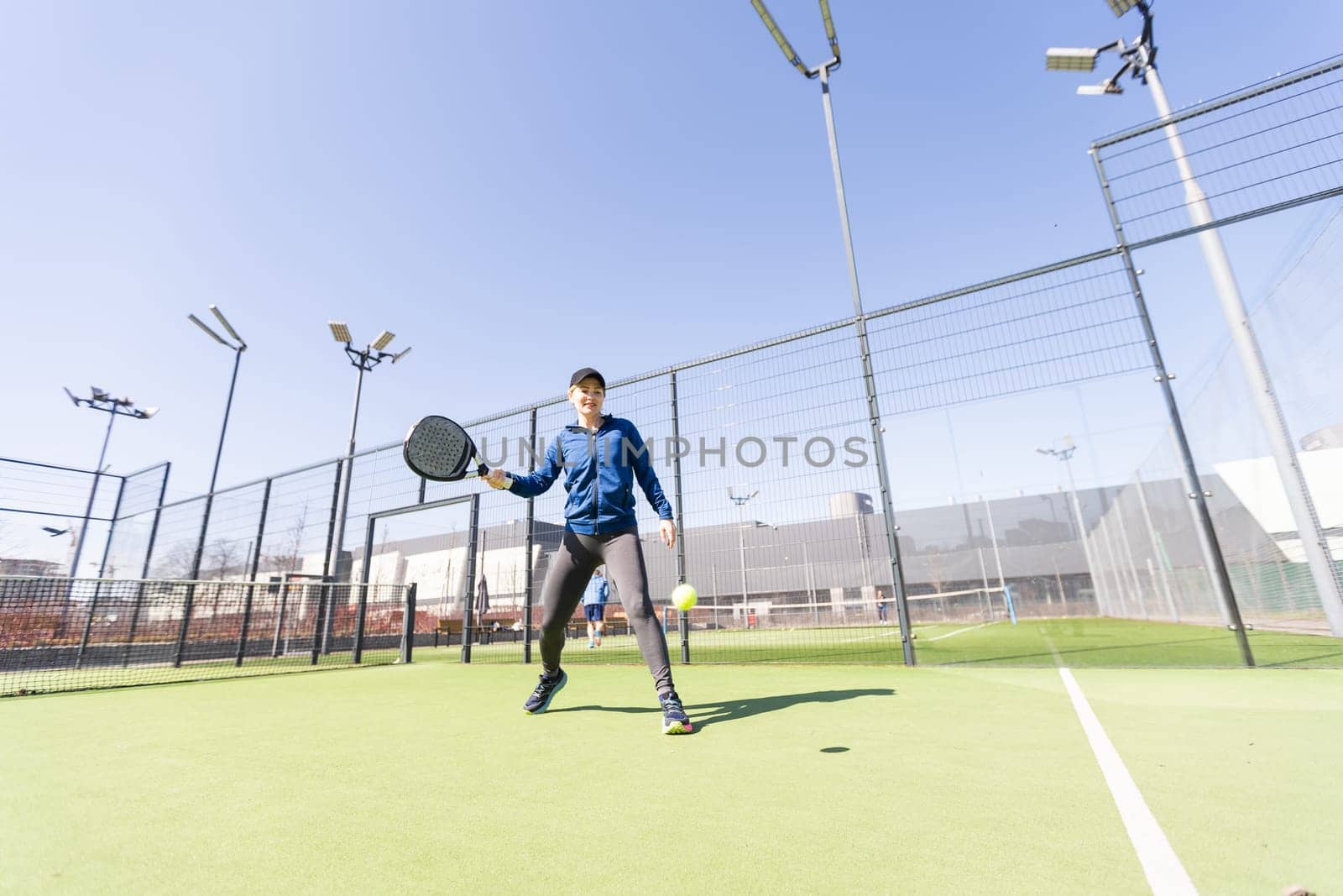 One woman with racquet and ball behind the net in paddle tennis court ready for training. High quality photo