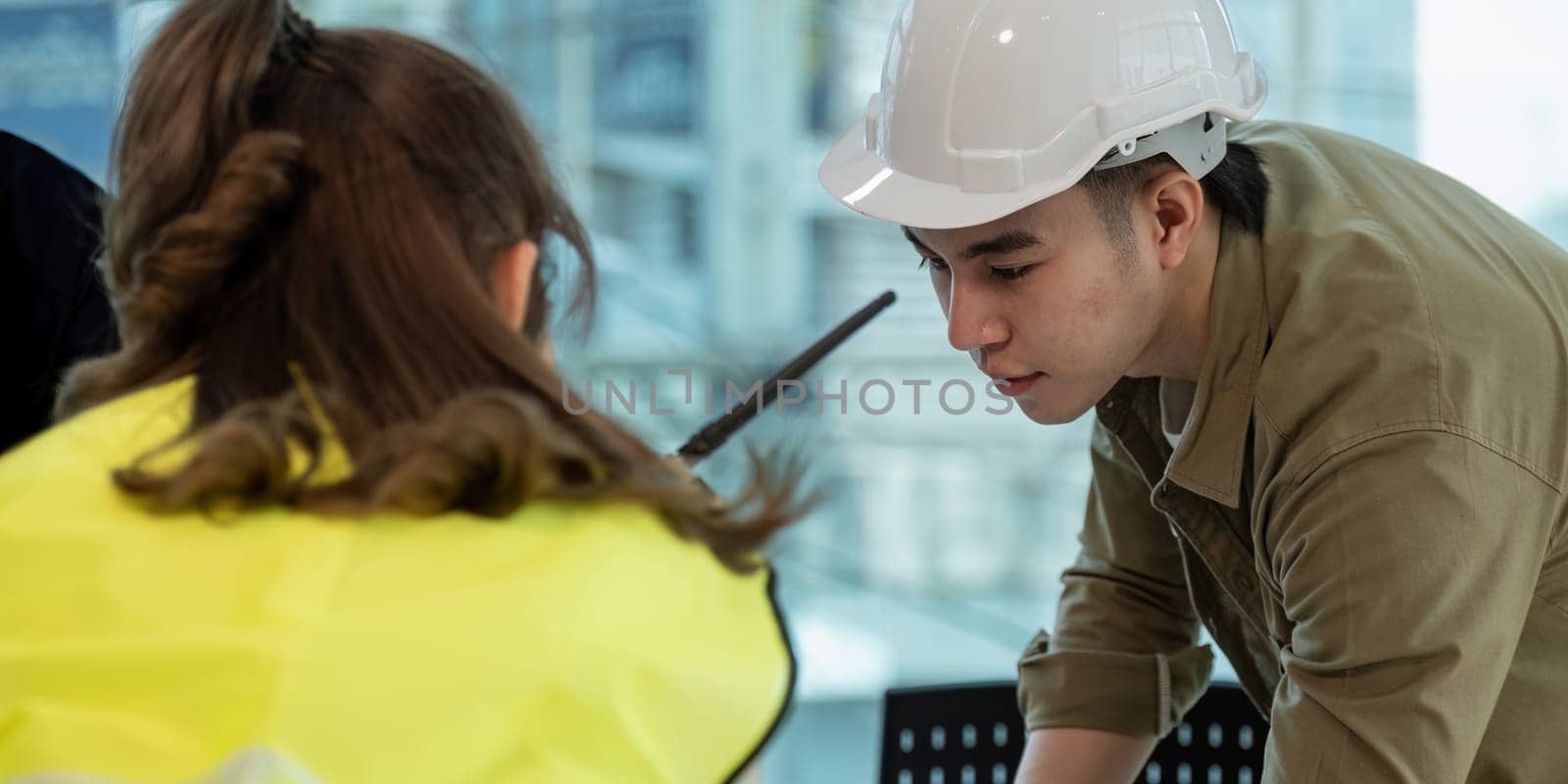 Teamwork in construction site, civil engineer or professional foreman in safety helmet hard hat using blueprint in while standing at industrial factory, teamwork concept by nateemee