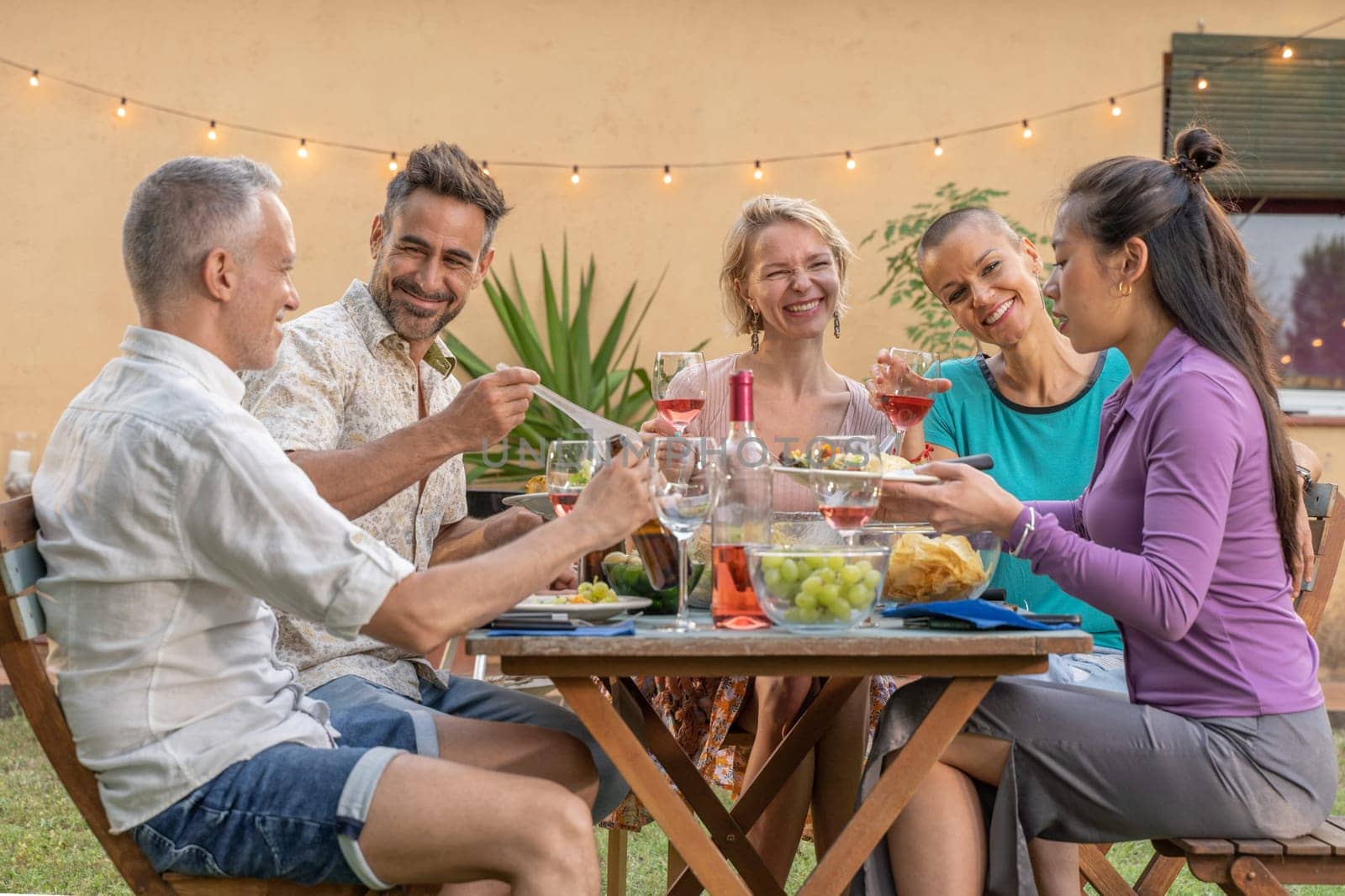 Friends eating and drinking happy smiling and laughing in the patio. Middle-aged cheerful people around the table on summer vacations. by PaulCarr