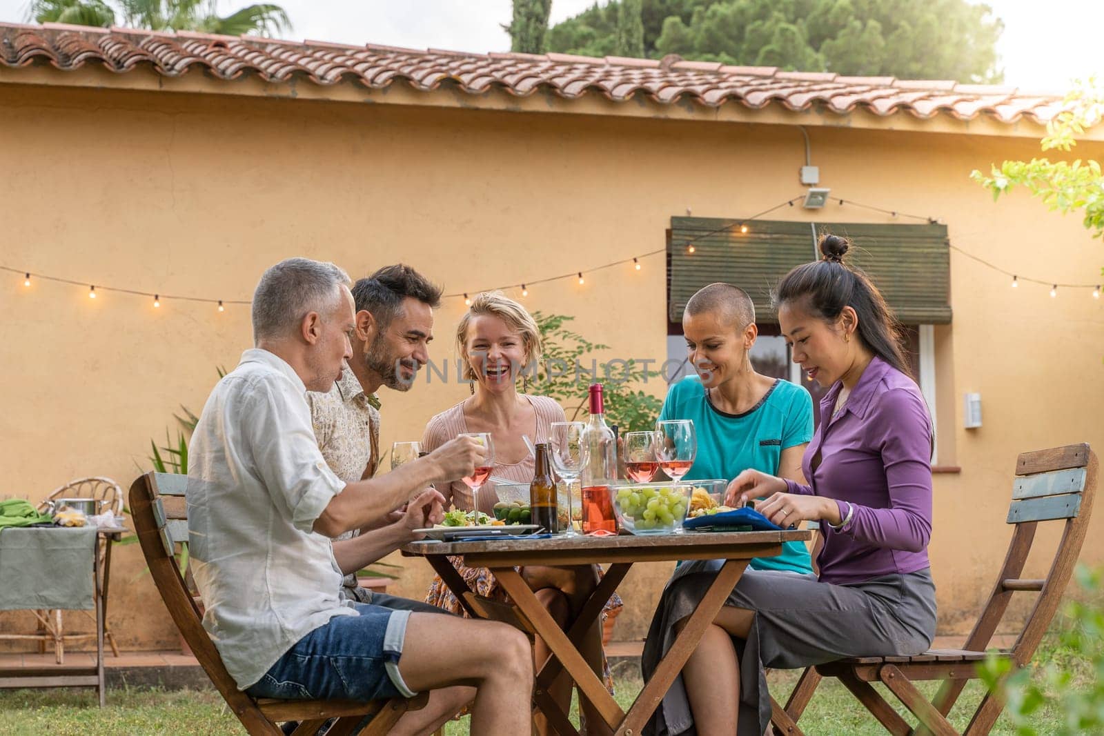 Multiethnic family eating happy smiling and laughing in the backyard at home. High quality photo