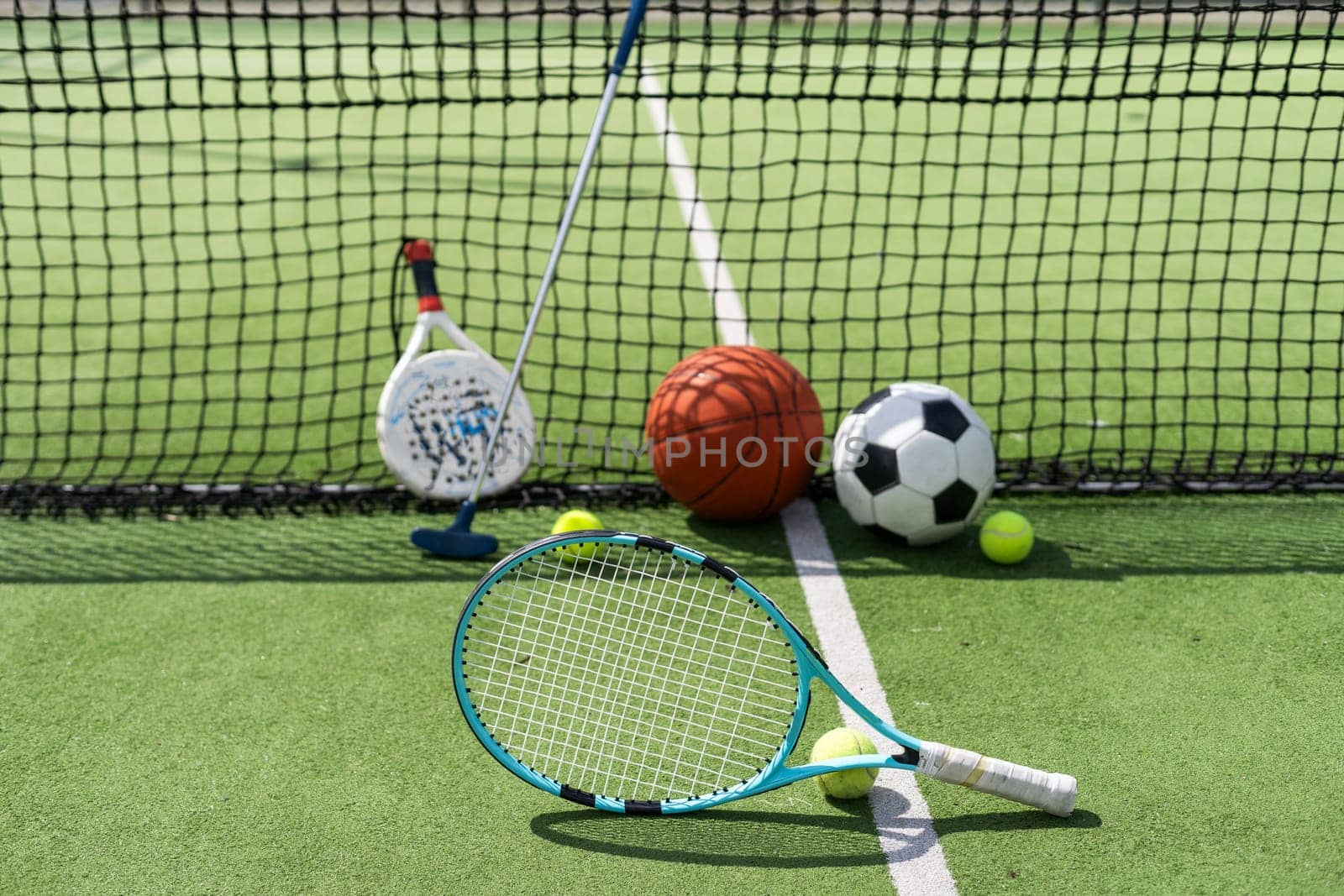 football soccer ball basketball tennis ball and racket laid on grass at sunset by Andelov13