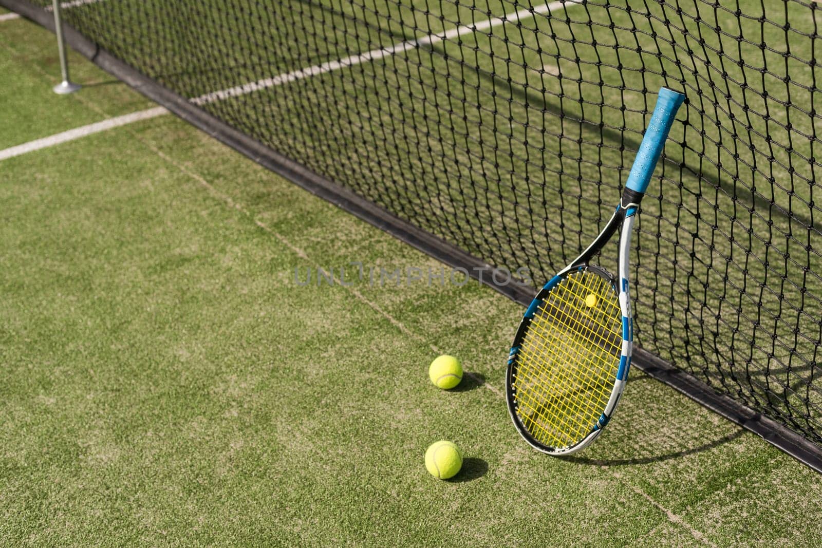 Tennis racquet and tennis balls at the net on the lines on a tennis court. by Andelov13