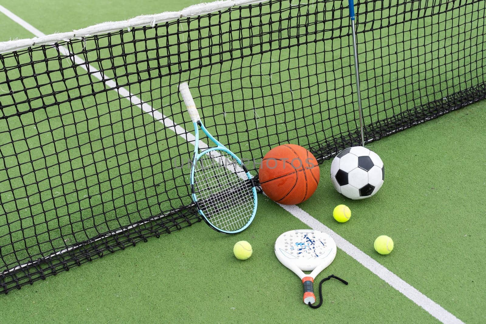 A variety of sports equipment including an american football, a soccer ball, a tennis racket, a tennis ball, and a basketball. High quality photo