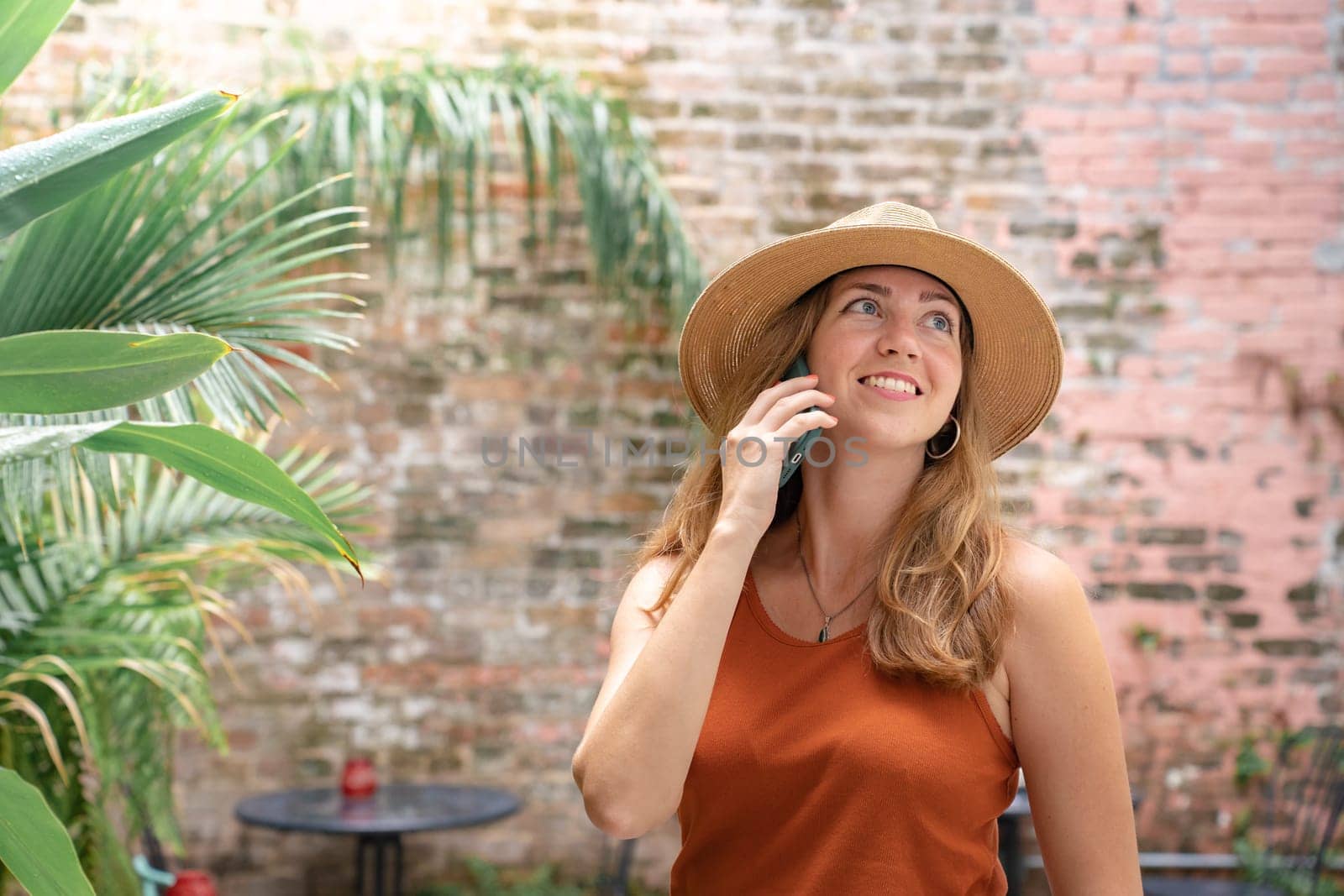 Happy woman in a sun hat smiling while talking on a cellphone. High quality photo