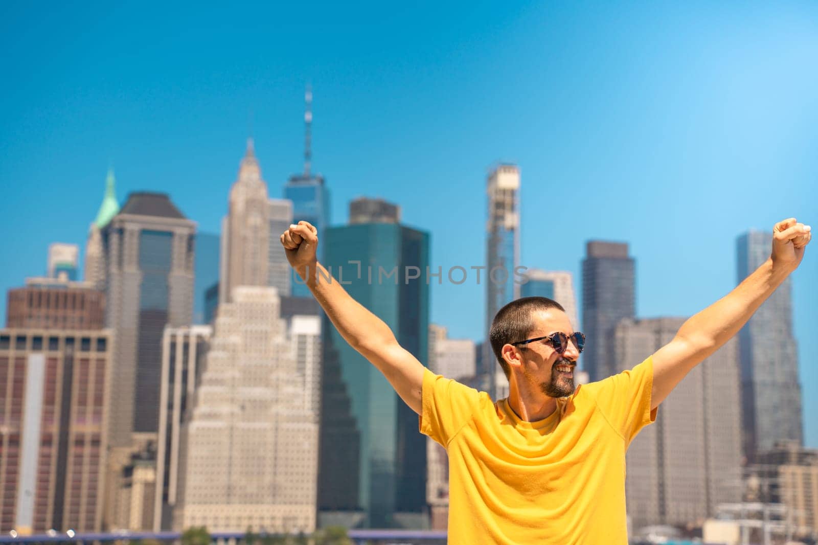Young attractive man with raised arms happy smiling win celebration in the city skyline. by PaulCarr