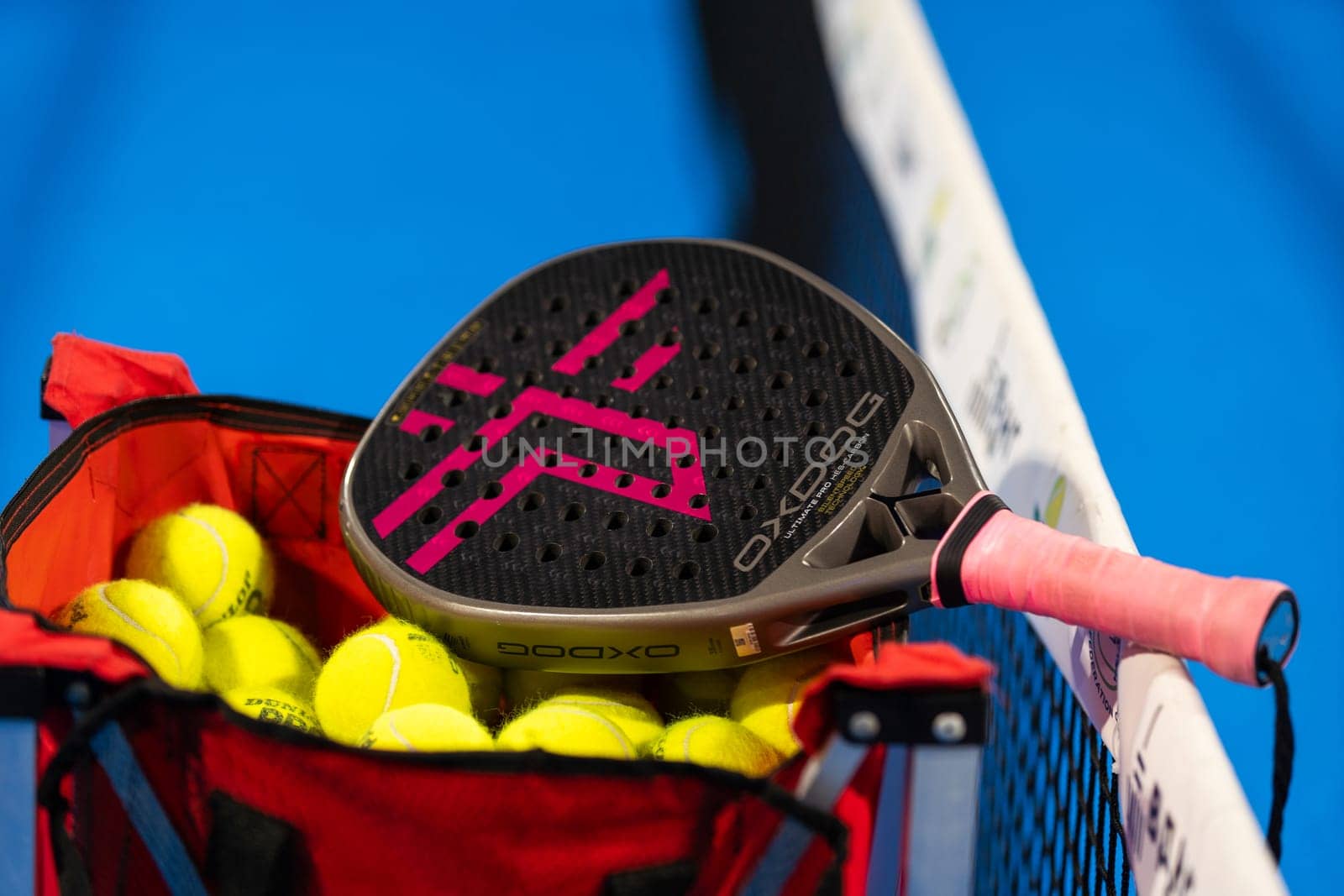 Kyiv, Ukraine, April 18, 2024. Black professional paddle tennis racket and ball with natural lighting on blue background. Horizontal sport theme poster, greeting cards, headers, website and app by Andelov13