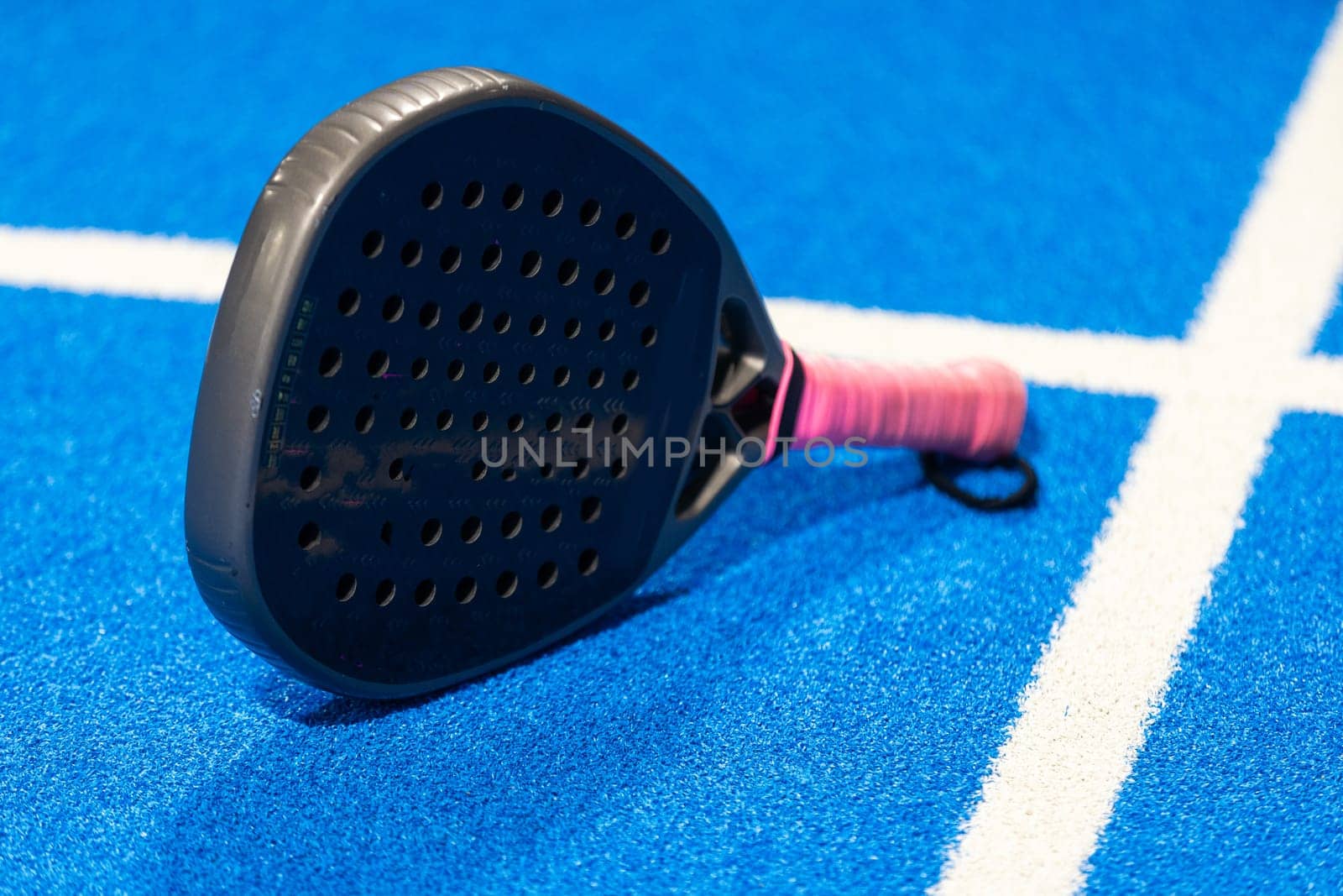 Black professional paddle tennis racket and ball with natural lighting on blue background. Horizontal sport theme poster, greeting cards, headers, website and app. High quality photo