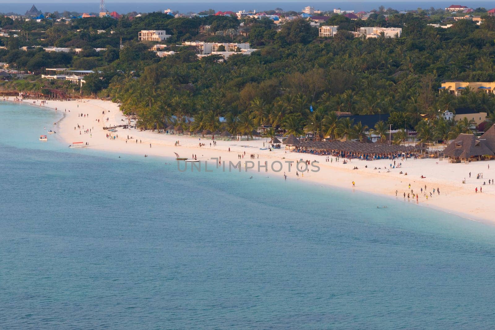 Zanzibar beach with a lot of people, background luxury resort and palm trees. Scene is relaxed and fun, summer concept, Tanzania, Zanzibar