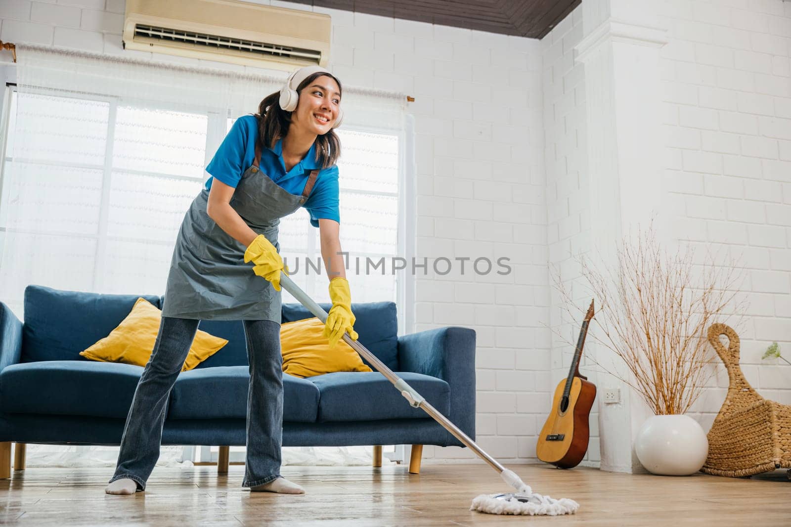 Asian teenager vibrant cleanup, maid sings dances in headphones. Joyful occupation blended with music excitement. Modern cleaning with tech appeal. Happy and Fun During Cleaning by Sorapop