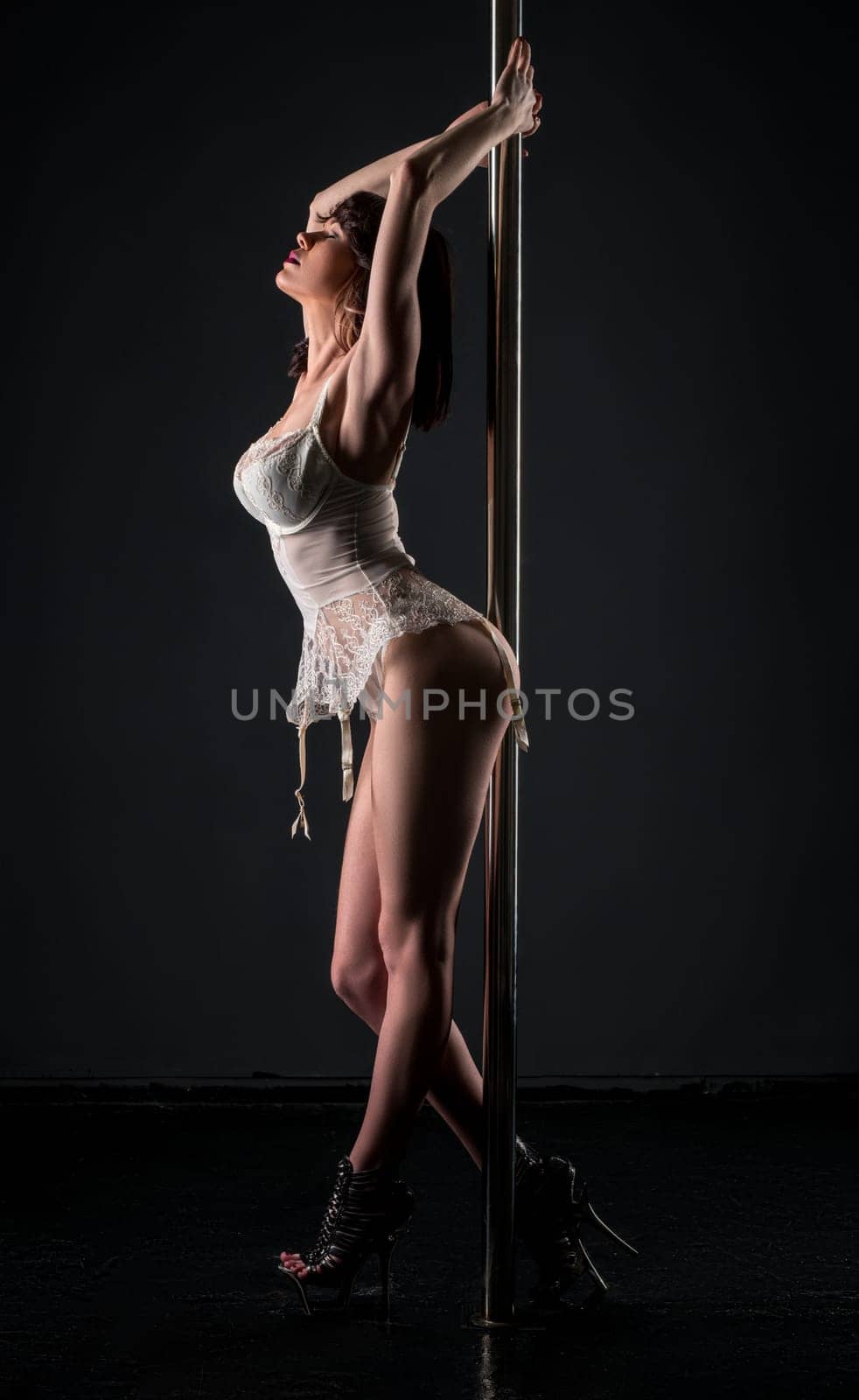 Photo of sensual woman in erotic corset posing with pylon