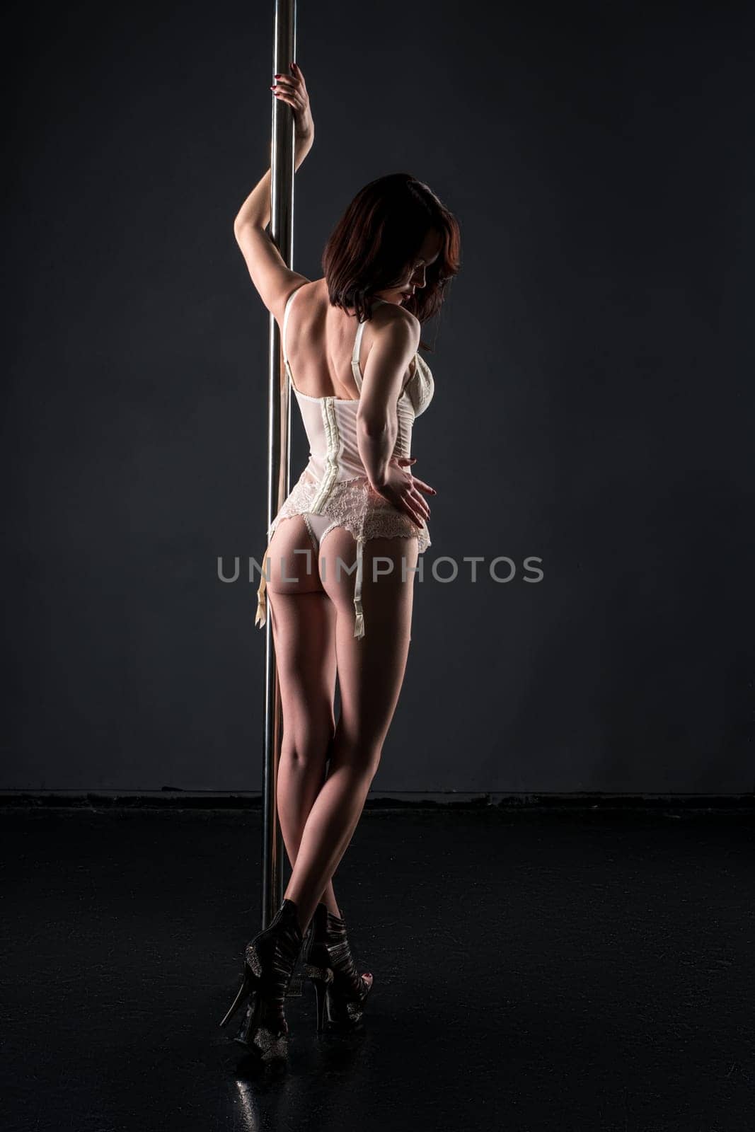 Rear view of dancer on the pole posing in sexy lingerie